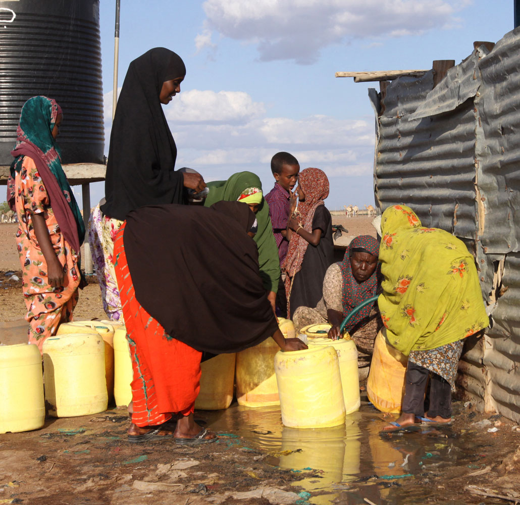 Kvinnor hämtar vatten vid ett borrhål i den kenyanska byn Dertu.