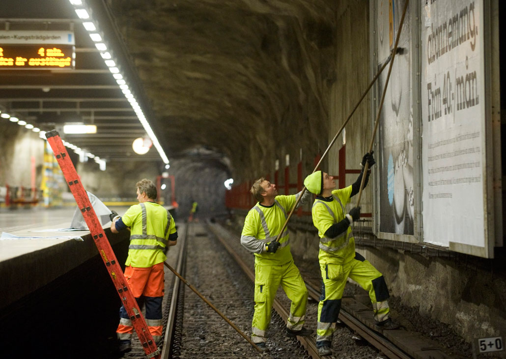 Peter Högberg och Tim Carlberg klistrar snabbt och metodiskt, samtidigt som Robert Carlberg förbereder en klibbig affischdel. ”Att göra det här snabbt tar år att lära sig”, säger han. Om fyra minuter ska tåget komma.