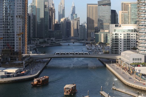 In this April 1, 2015 photo, tourists and visitors enjoy their dhow cruise trips at the Marina water canal as a tram crosses on a bridge in Dubai, United Arab Emirates. Dubai Marina is finally coming into its own after years of seemingly endless construction work. Hewn out of the desert and connected to the Persian Gulf by channels at each end, the 3.5 kilometer (2.2 mile) U-shaped canal would be an engineering marvel even without its skyline. (AP Photo/Kamran Jebreili)
