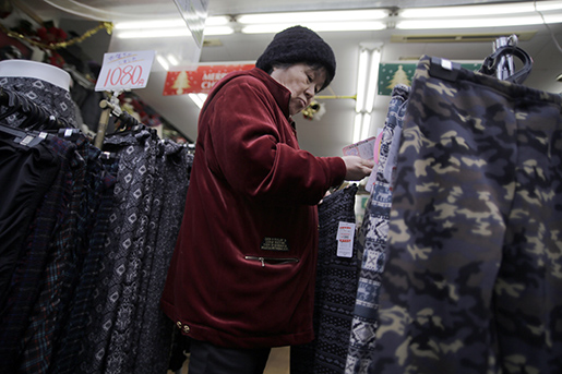 En kvinna tittar på kläder i en butik i Tokyo, Japan, där regeringen manar allmänheten att shoppa mer. Foto: AP Photo/Eugene Hoshiko