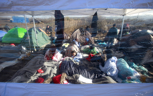 Syriska flyktingar fotograferade genom tältväggen, nära gränsen mellan Makedonien och Serbien. Foto: AP Photo/Boris Grdanoski