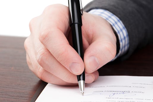 Male signing documents with black pen on a desk