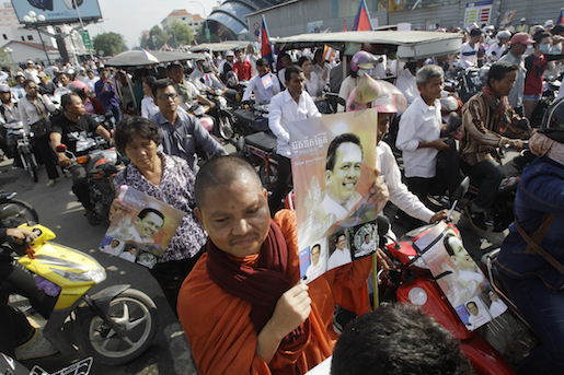 A Cambodian Buddhist monk, foreground, holds a portrait of Cambodia prominent political analyst Kem Ley as he takes part in a funeral procession of Kem Ley in Phnom Penh, Cambodia, Sunday, July 24, 2016. Tens of thousands of Cambodians marched Sunday, in the funeral procession for the leading government critic who was fatally shot in an attack that raised suspicion of a political conspiracy. (AP Photo/Heng Sinith)