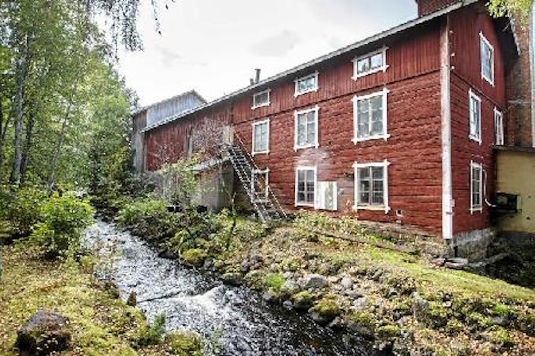 En röd träbyggnad vid en fors