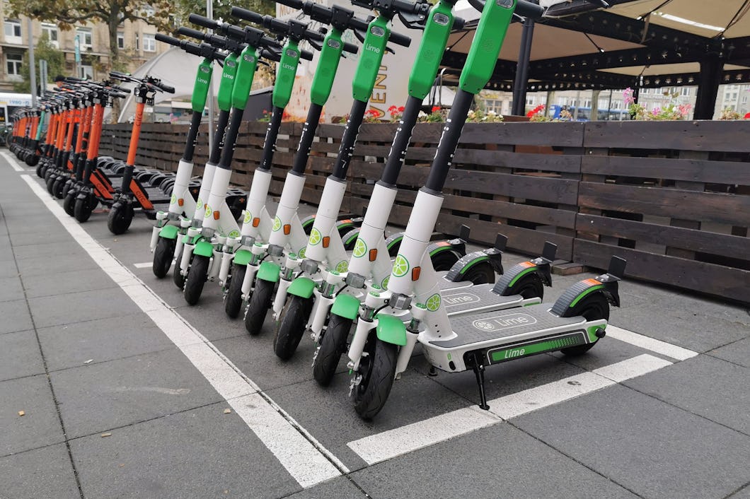 En lång rad parkerade elsparkcyklar i stadsmiljö.