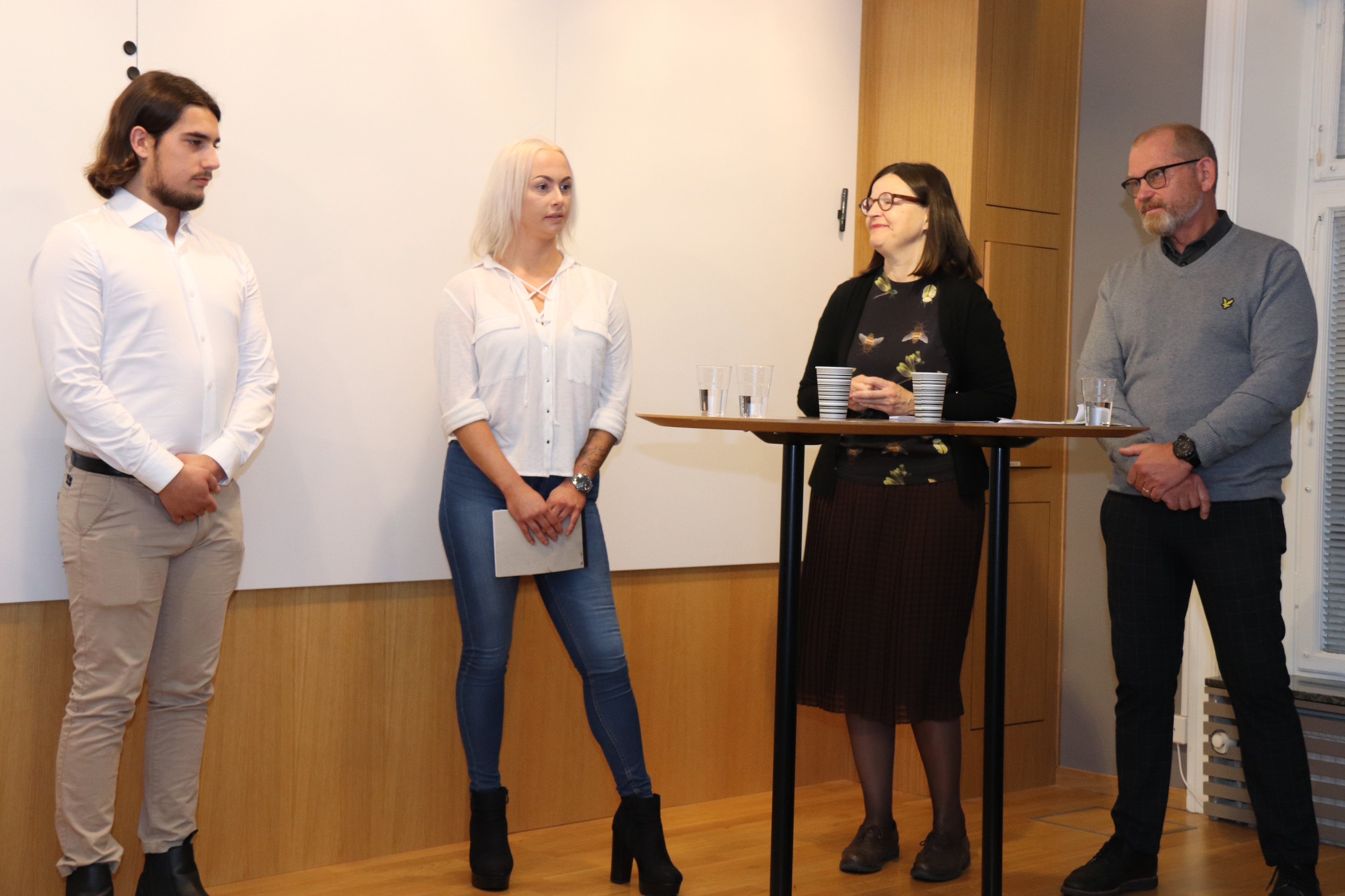 Fyra personer står längst fram i en föreläsningssal.