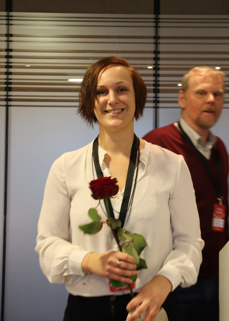 Louise Olsson leende med en ros i händerna.