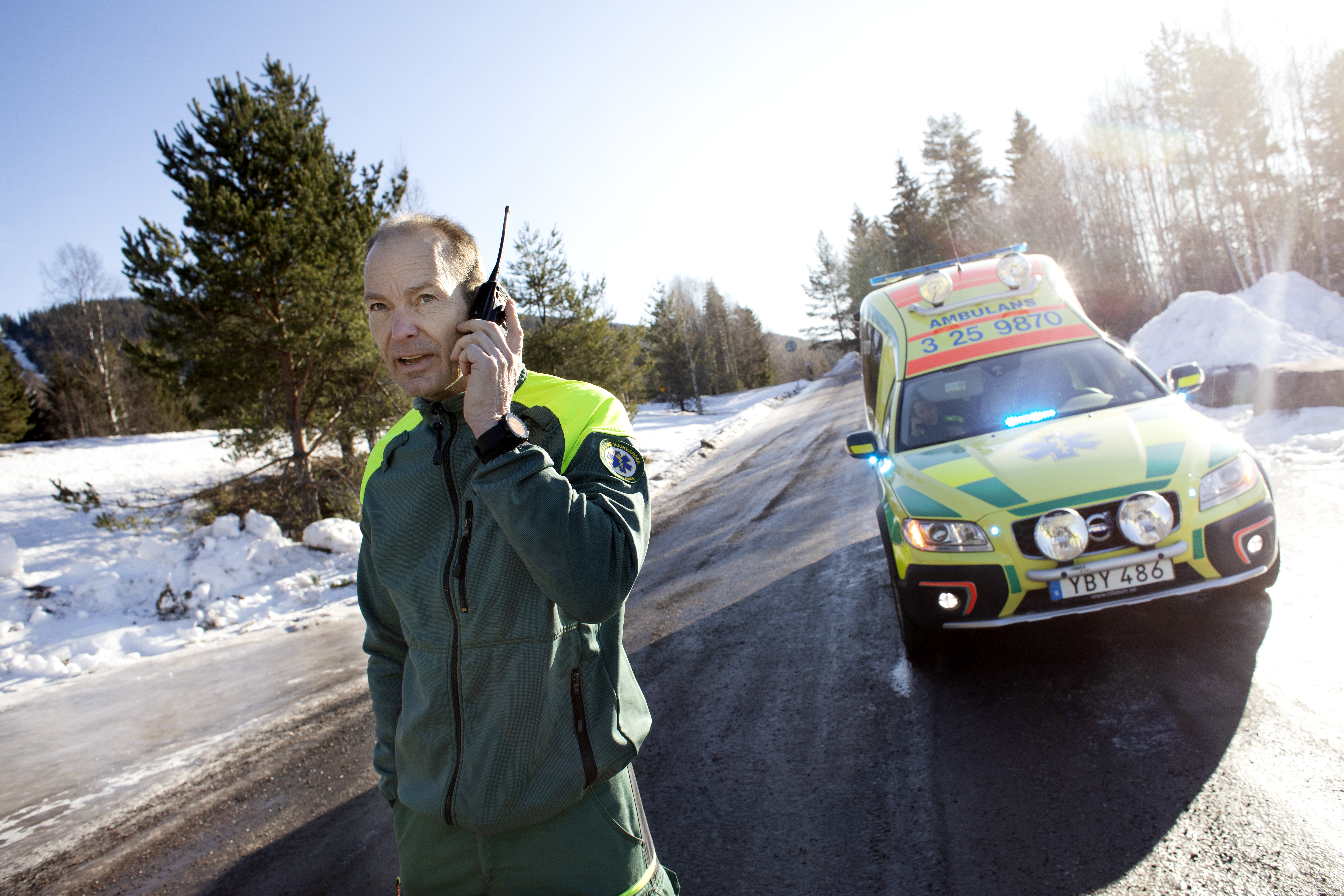 Mats kommunicerar med SOS Alarm. I ambulansen bakom vårdas ett barn med andningssvårigheter.