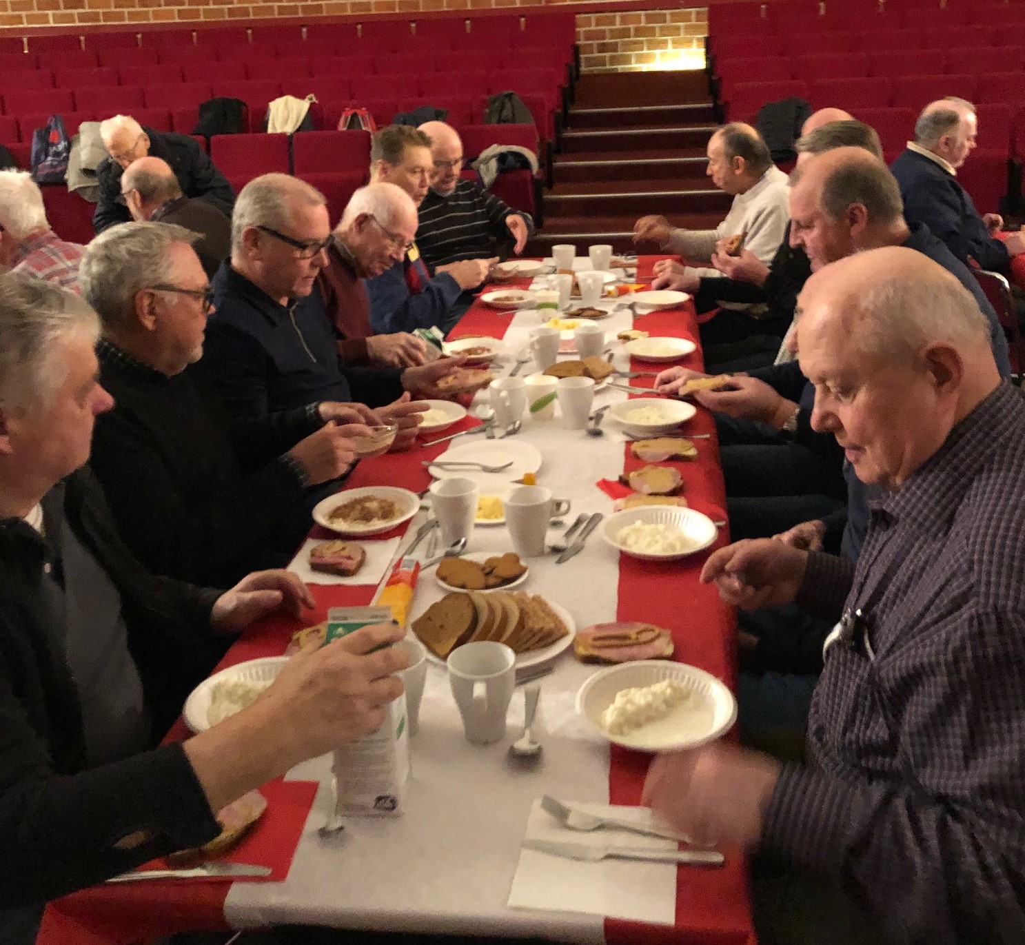 Ett fyrtiotal personer längs ett långt bord, alla äter gröt.