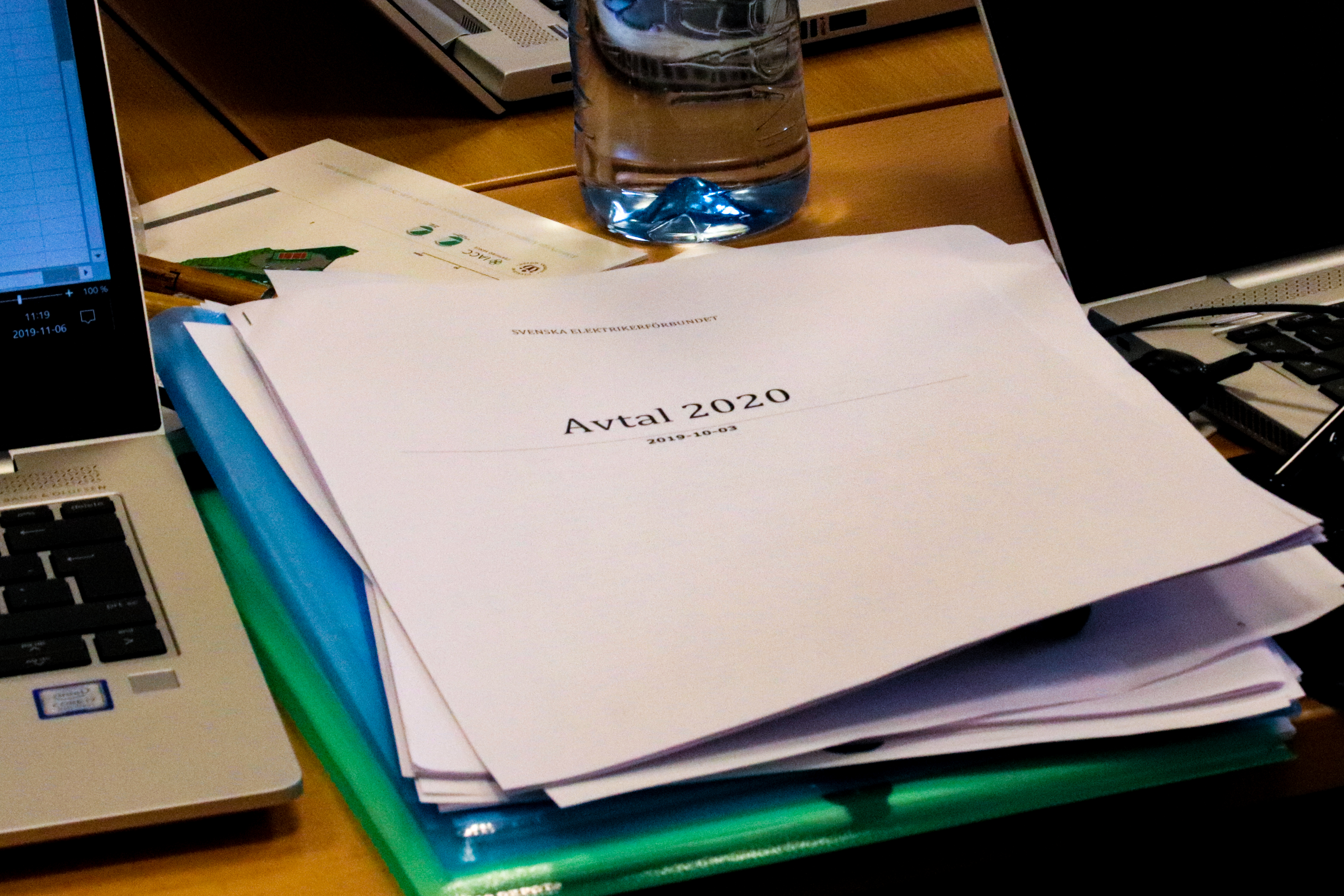 En bunt papper på ett mötesbord, med texten Avtal 2020 på omslaget