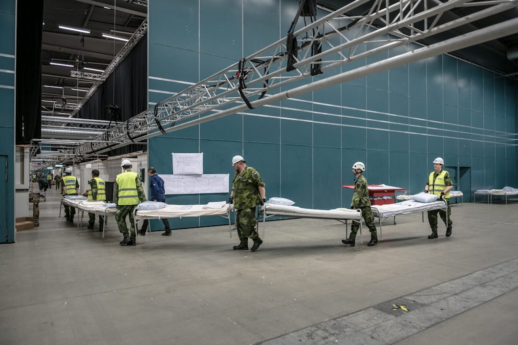 En samling personer som bär in sängar i en byggnad