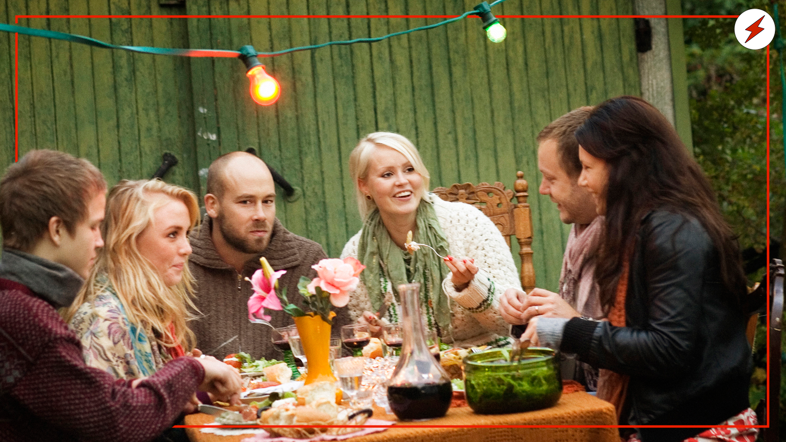 en samling personer runt ett altan-bord med mat på