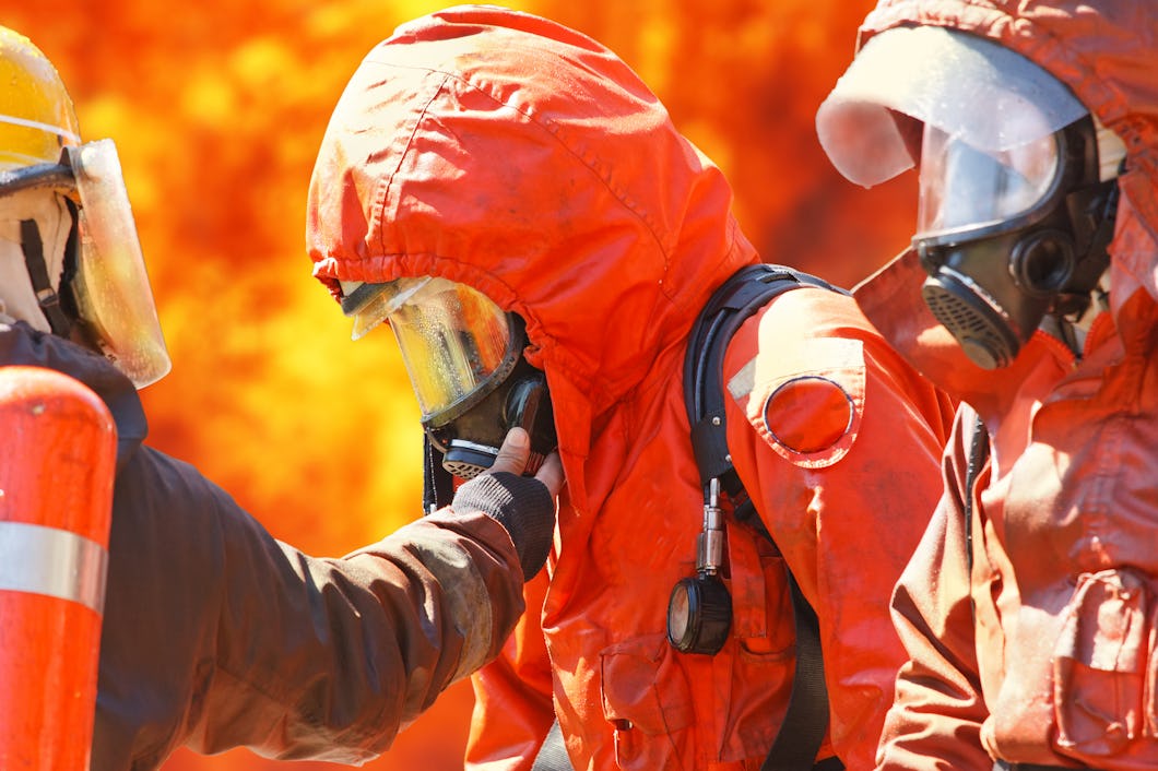 Personer i brandskyddskläder framför en skogsbrand