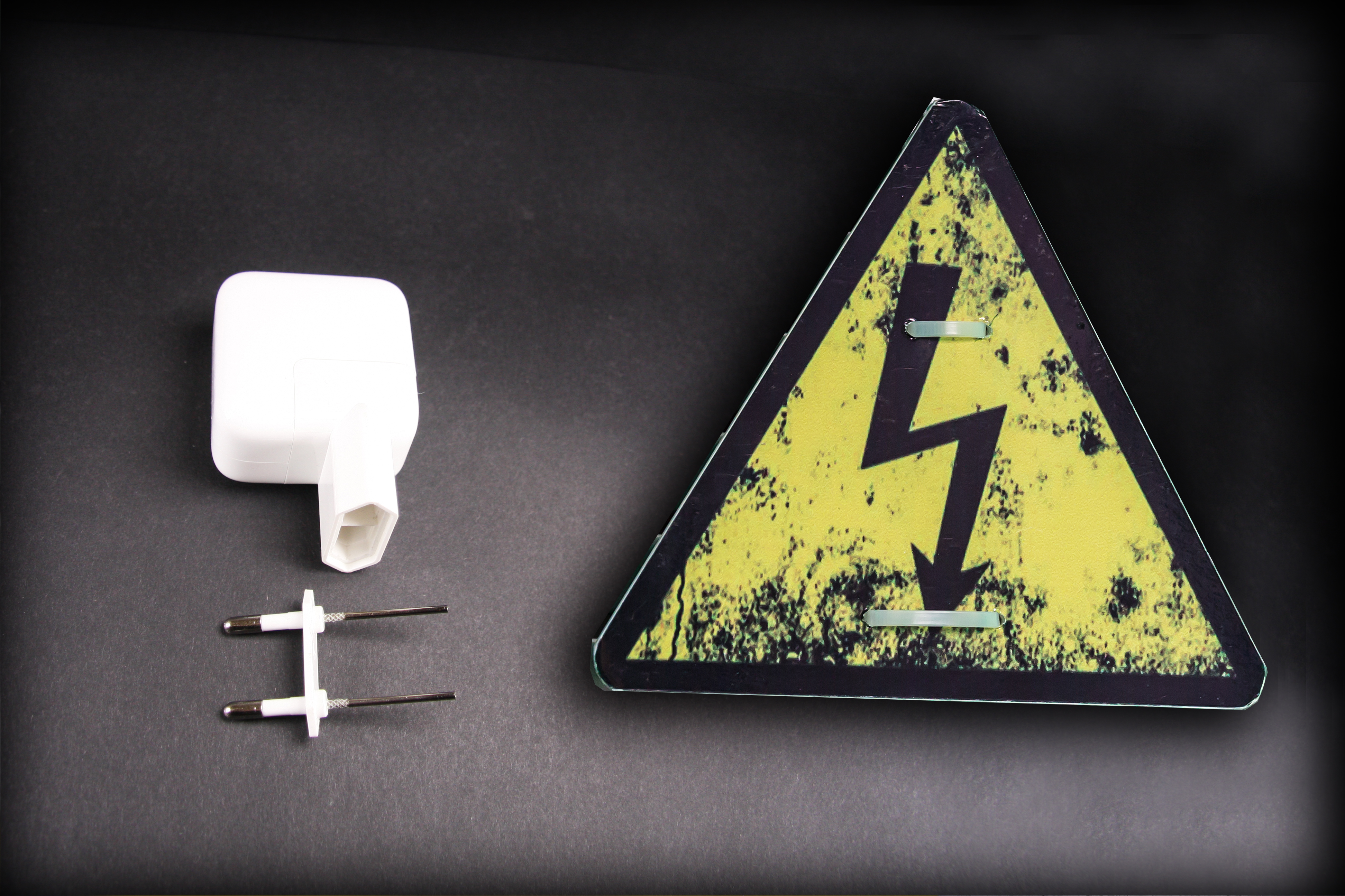 En trasig stickpropp invid en varningsskylt för elfara