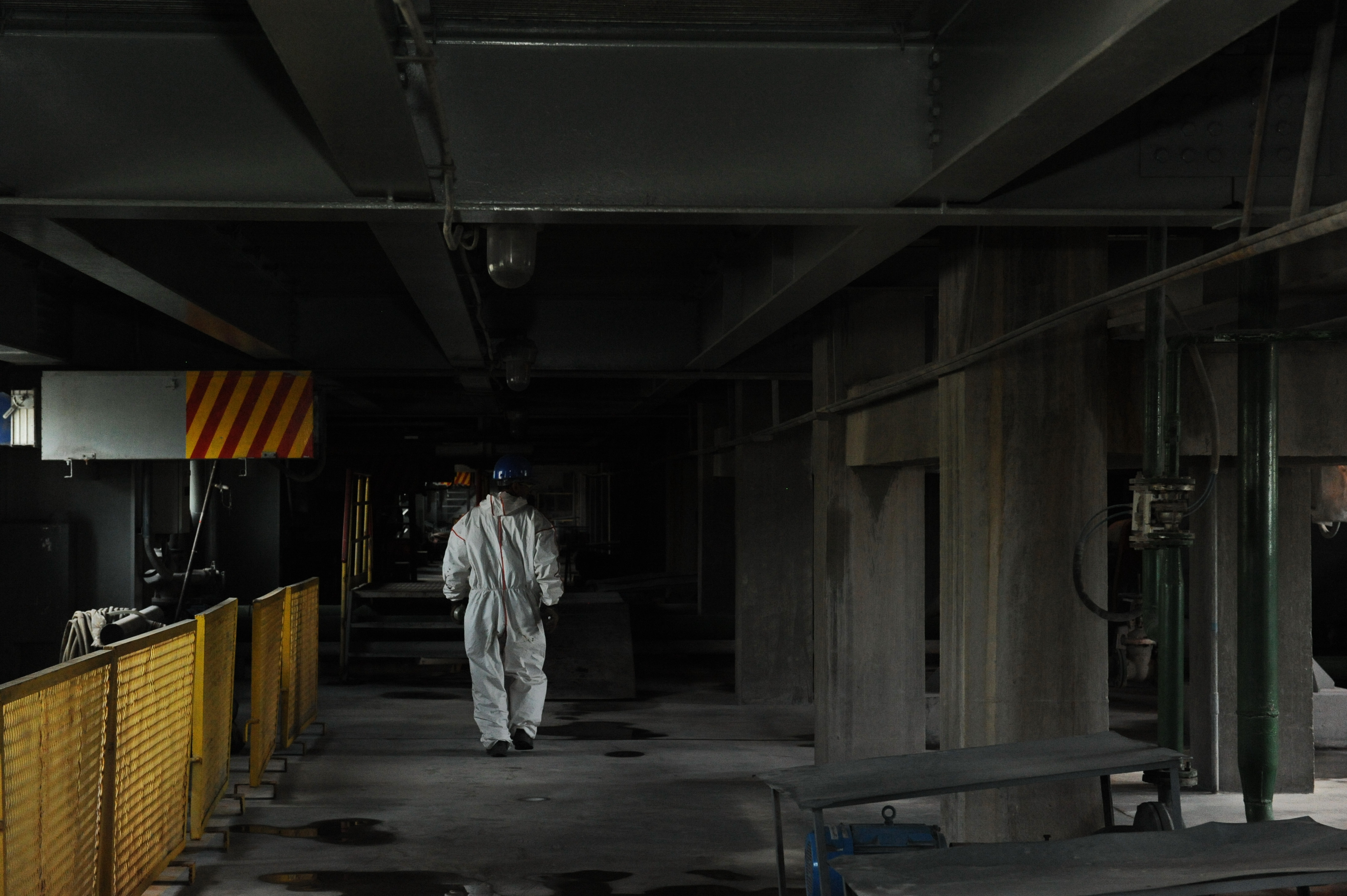 En arbetare i vit skyddsoverall går genom en källare