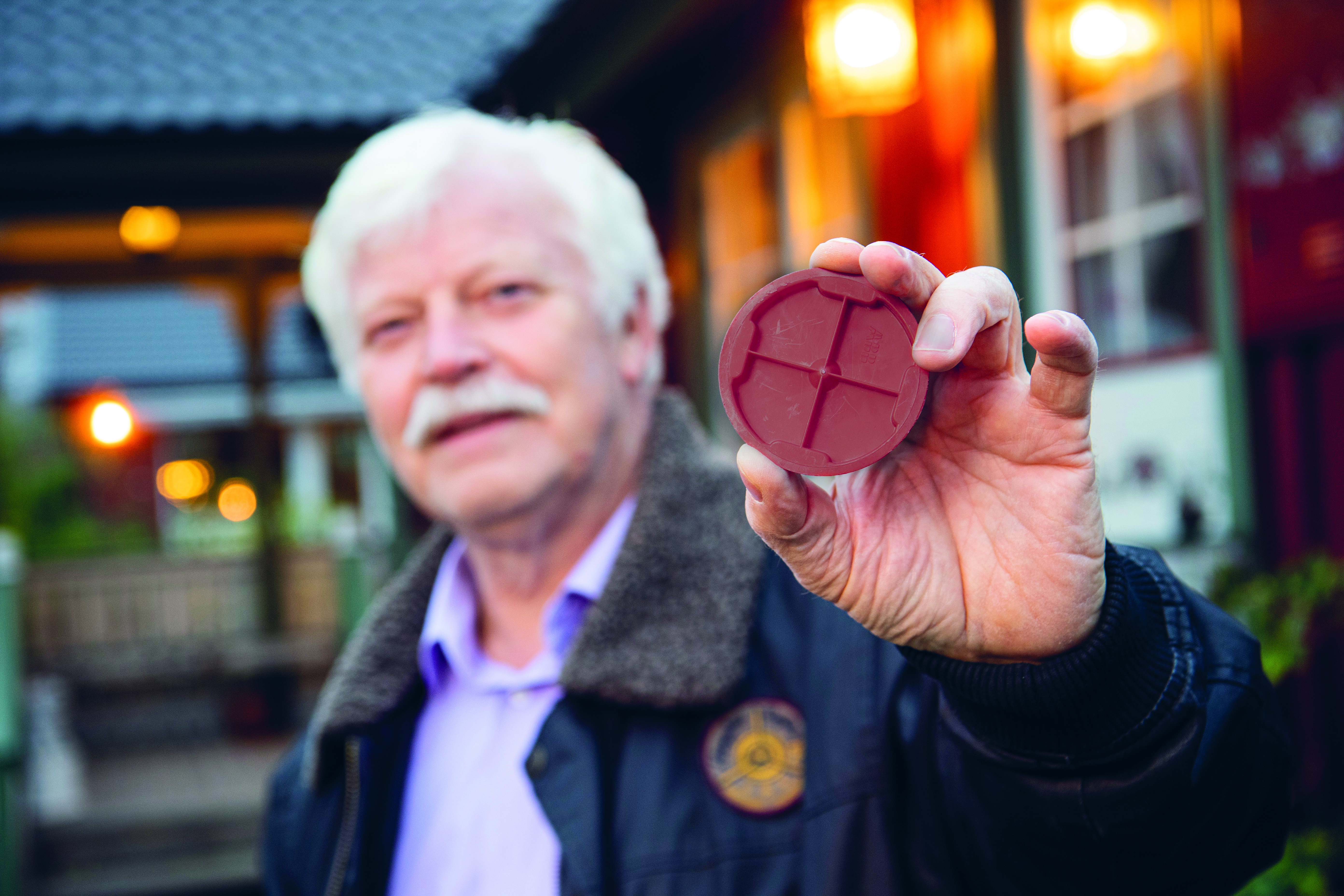 Sören Kling håller upp ett plastlock mot kameran