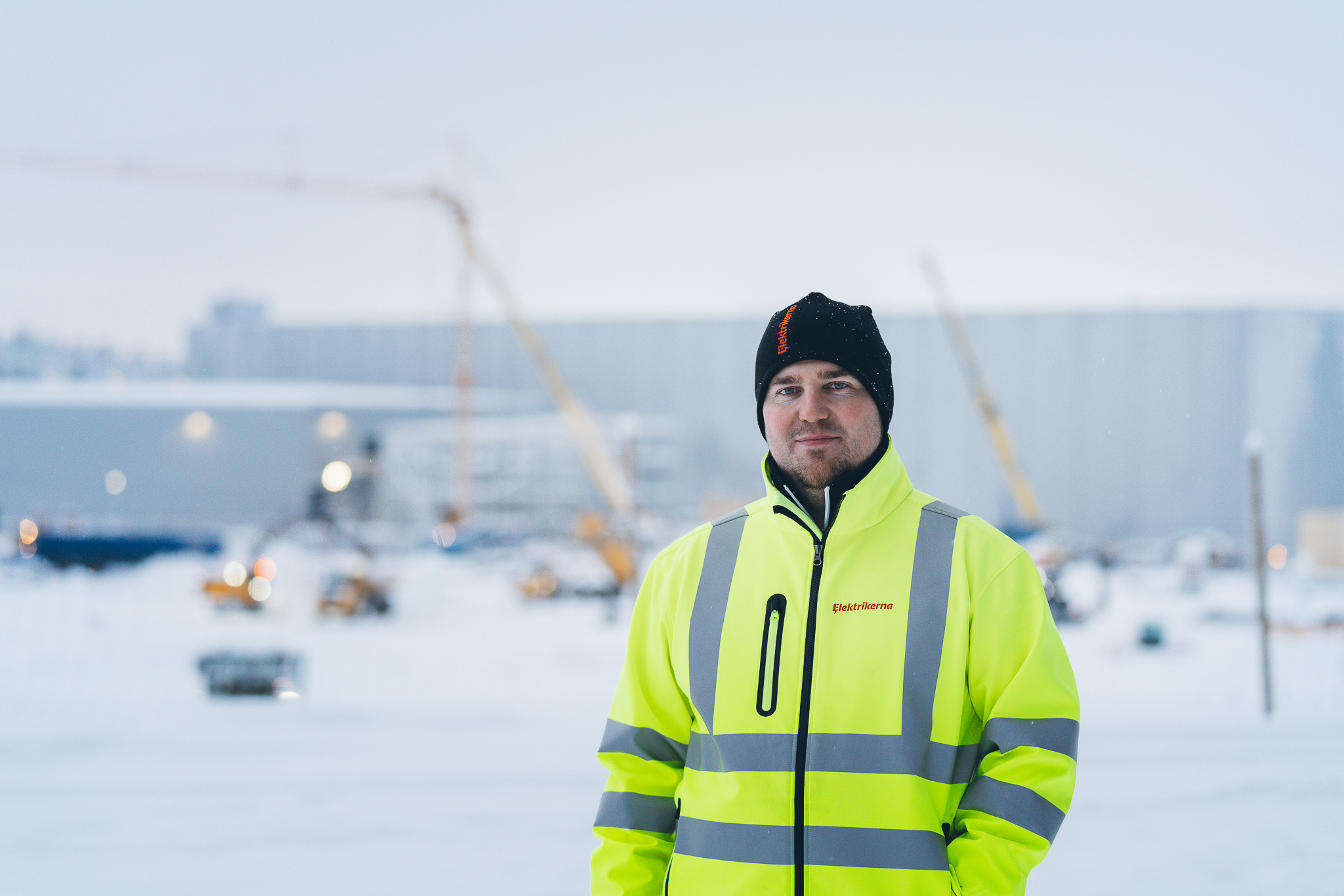 Mathias Hansson utomhus i snön, med arbetsplatsen i bakgrunden