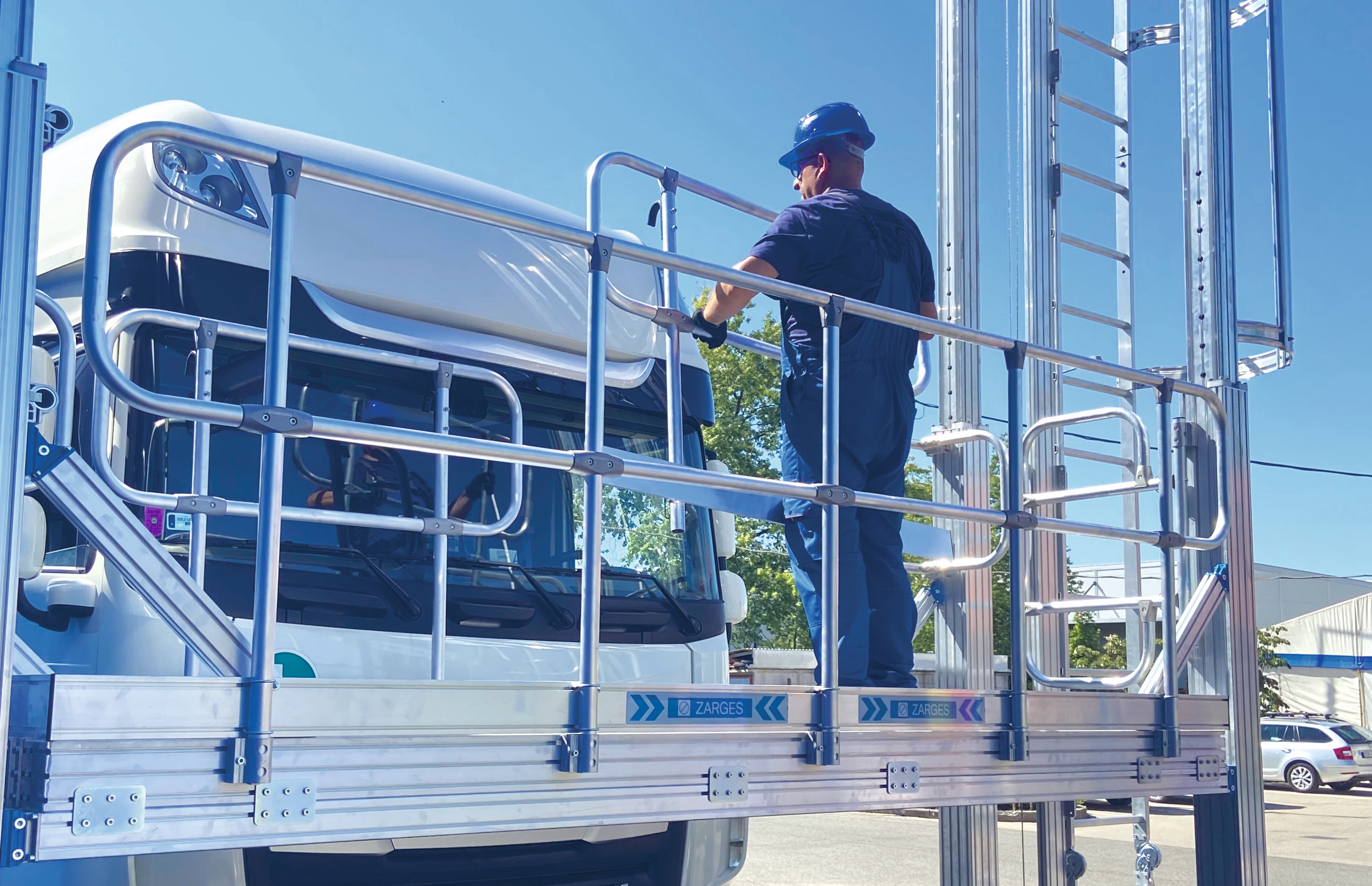 En person i bygghjälm på en plattform framför en lastbilsfront