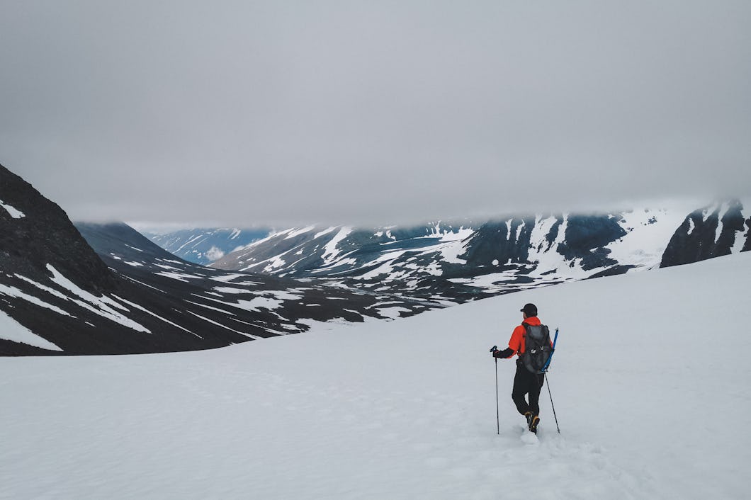 En person vandrar över en snöig slätt mot ett berg