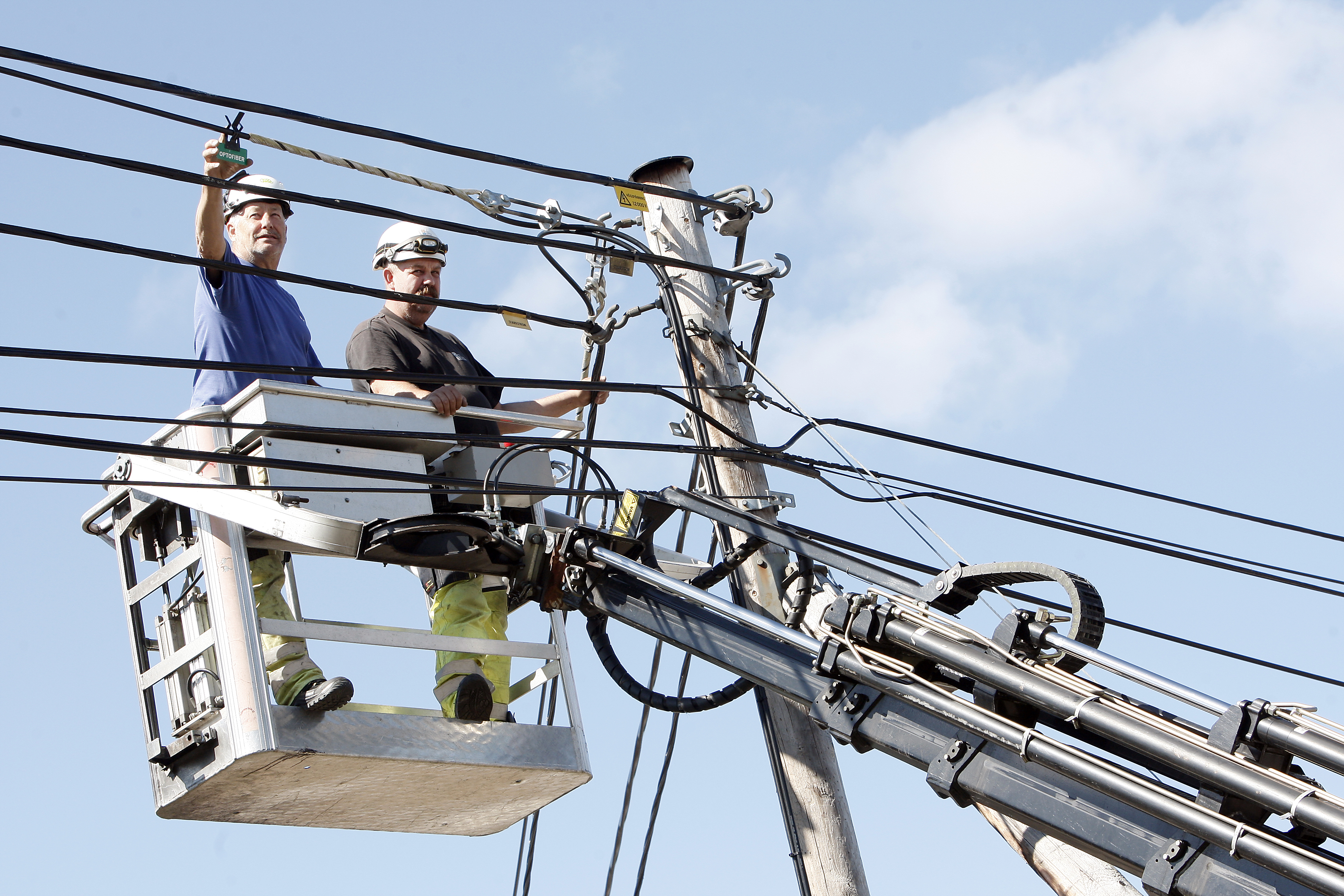 Två personer arbetar med elledningar från en skylift