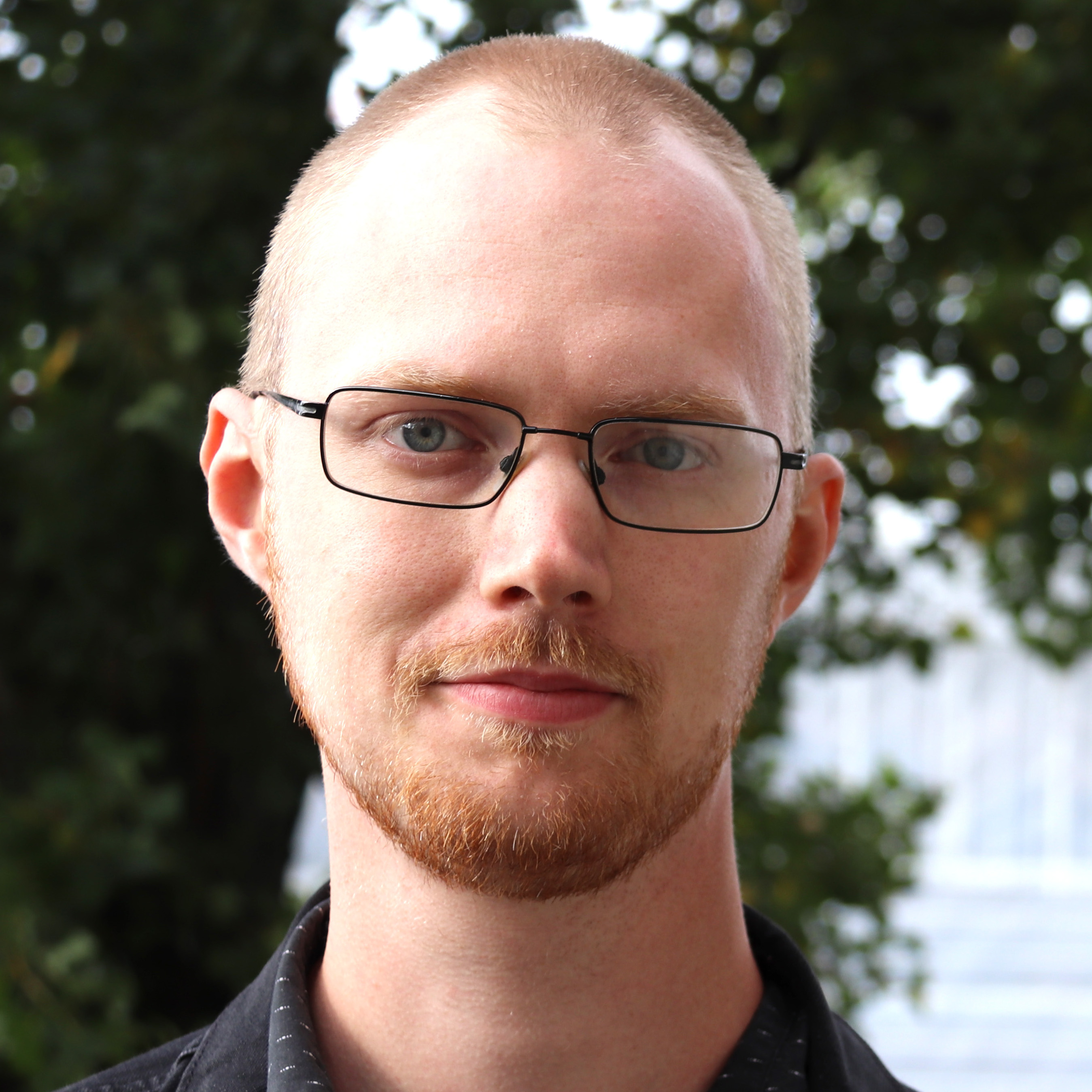 En man med glasögon tittar i kameran.