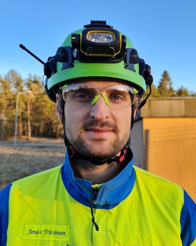 Jonas Strassman, i arbetskläder och med skyddshjälm. Poträttbild tagen utomhus.