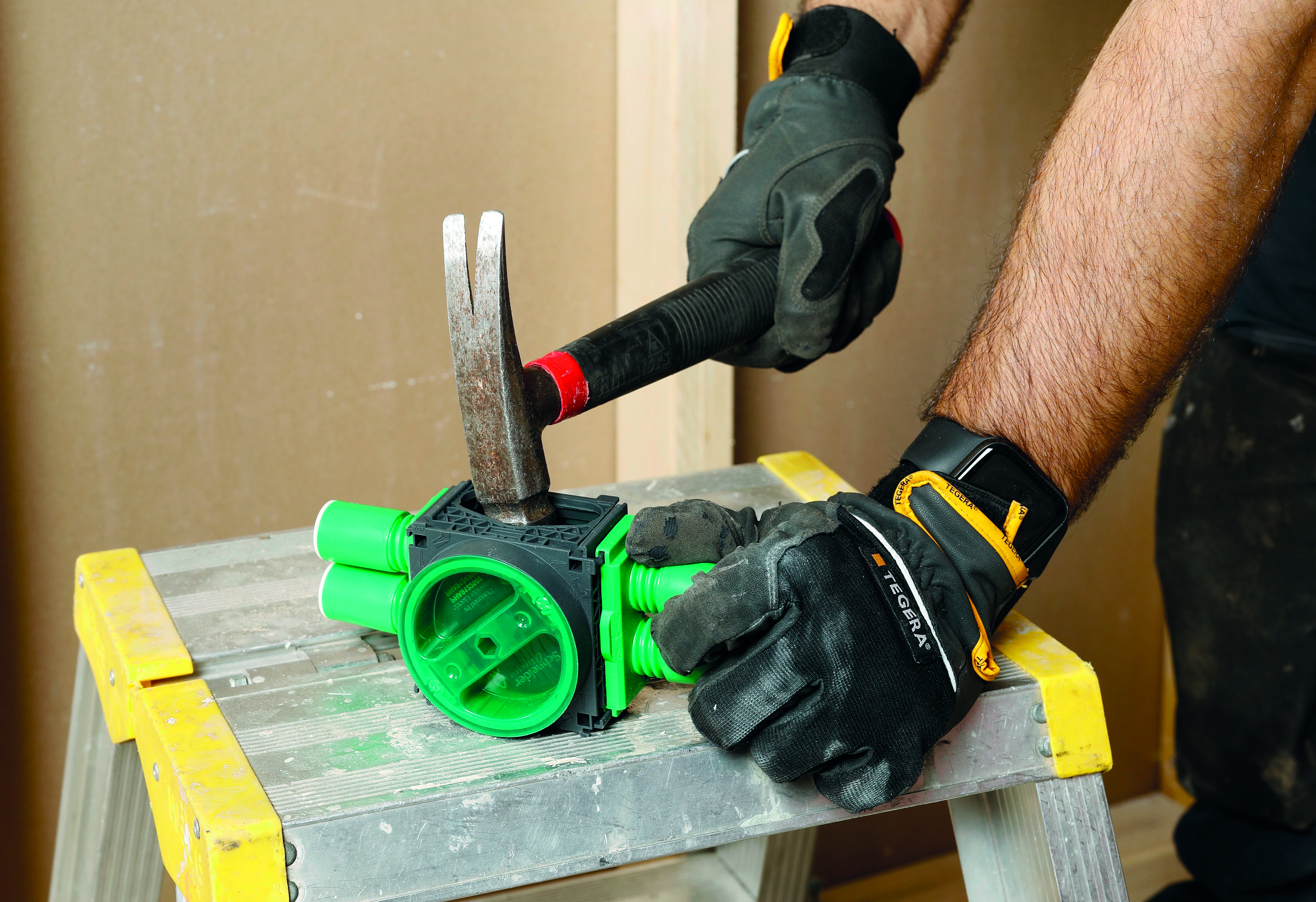 En person som slåt en hammare mot en grön plastdosa.