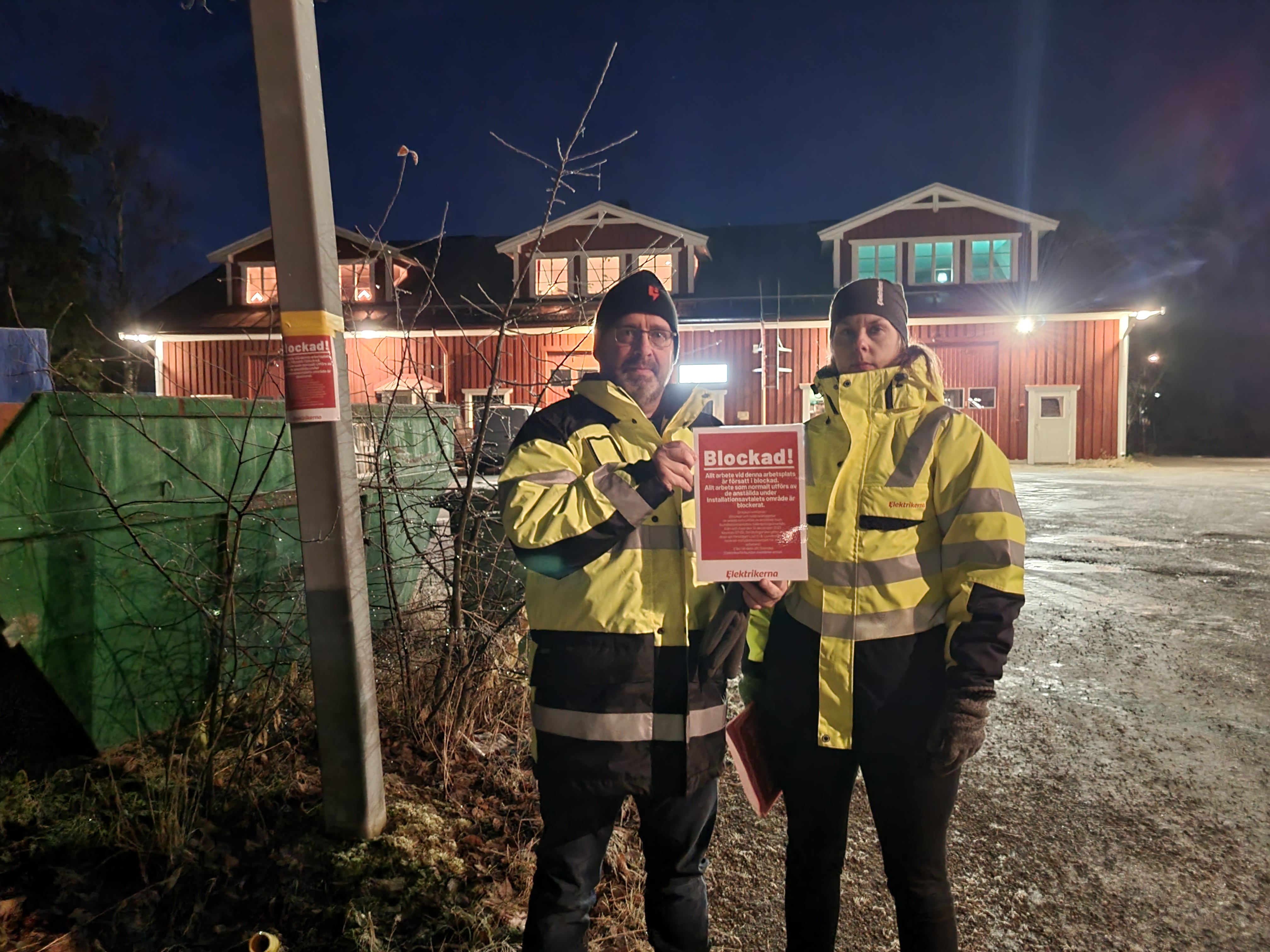 Michael Clysén och Karolina Dahl håller upp blockadskylt utanför en arbetsplats