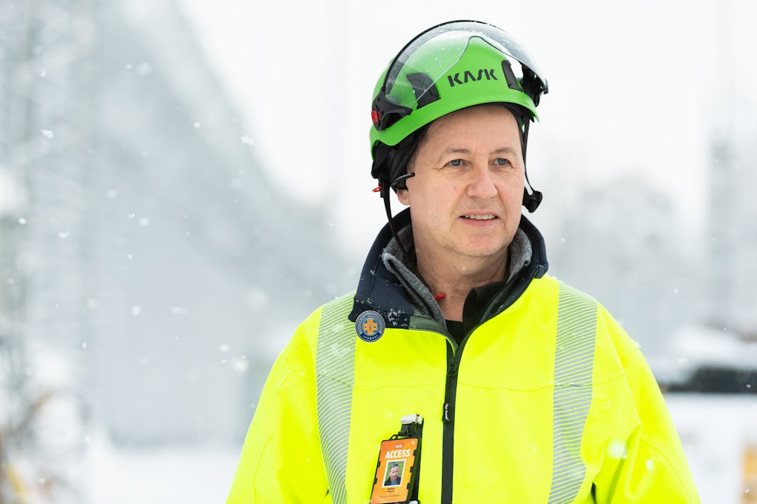Mikael Olsson utomhus i snön, iklädd grön hjälm och gul reflexjacka.