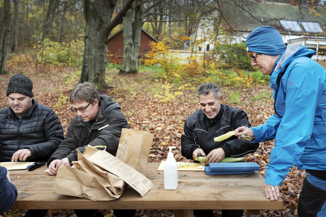 Mona Alvinsson Nilzon delar ut purjolök, morötter och potatis till Roger Larsson, Dennis Johansson och Mohammad Farhan Lababidi.