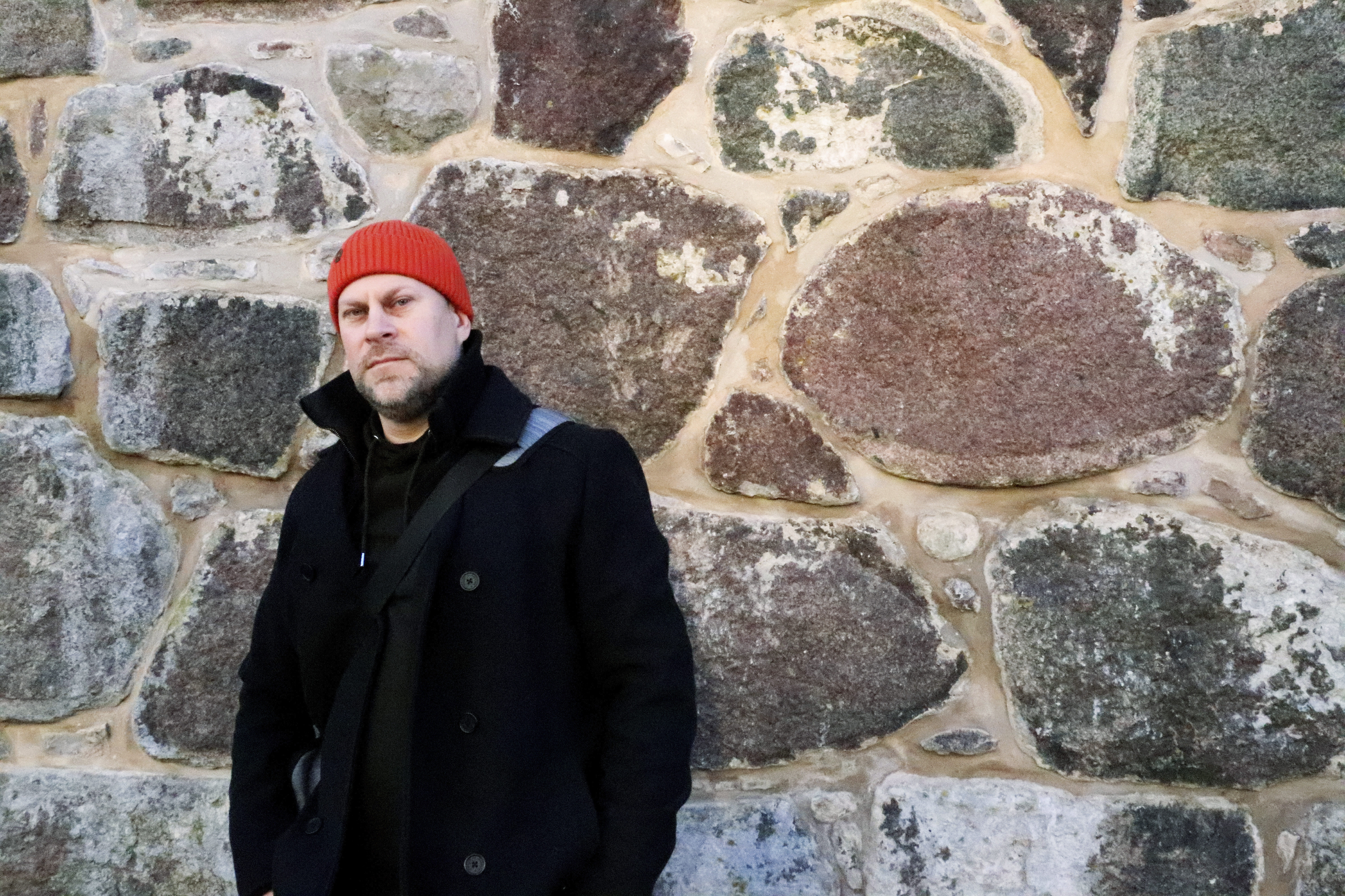Martin Karlbom framför en stenvägg utomhus