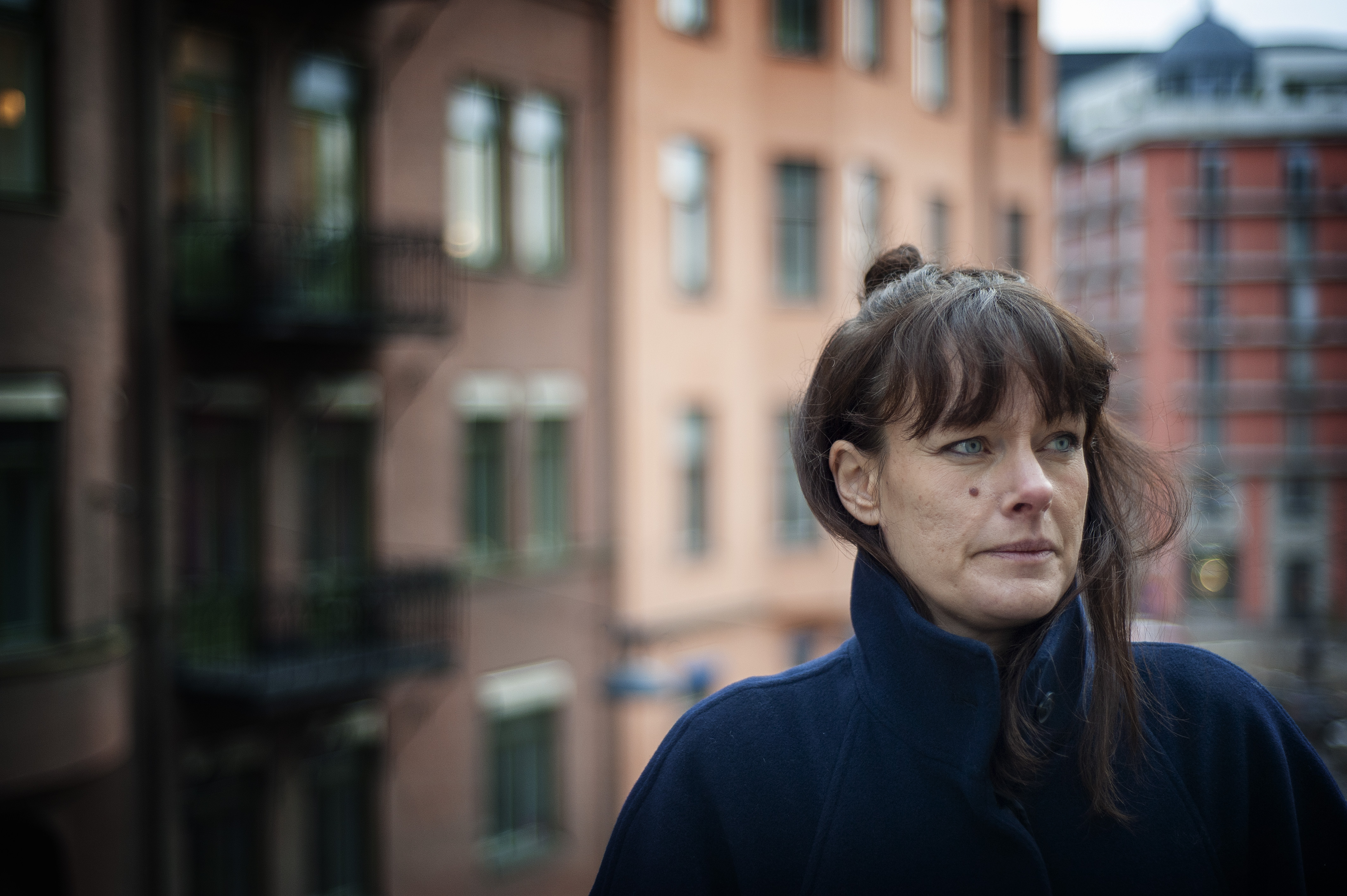 Maria Nyberg i blå kappa framför en husfasad.