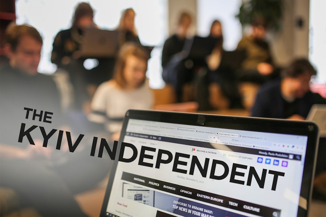 En samling människor, suddigt i bakgrunden, och längst fram del av en datorskärm där en hemsida syns. Över nedre delen av bilden står texten: The Kyiv Independent.