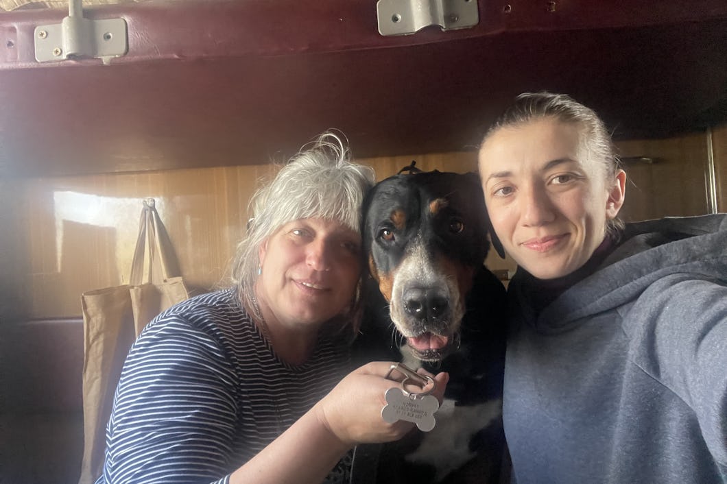 Ivanna Khrapko, i uppsatt hår och blå tröja, tar en selfie i en tågkupé. Längst till vänster sitter rektorn Sofia i blå tröja och vitt hår. I mitten sitter hunden "Duktig hund".