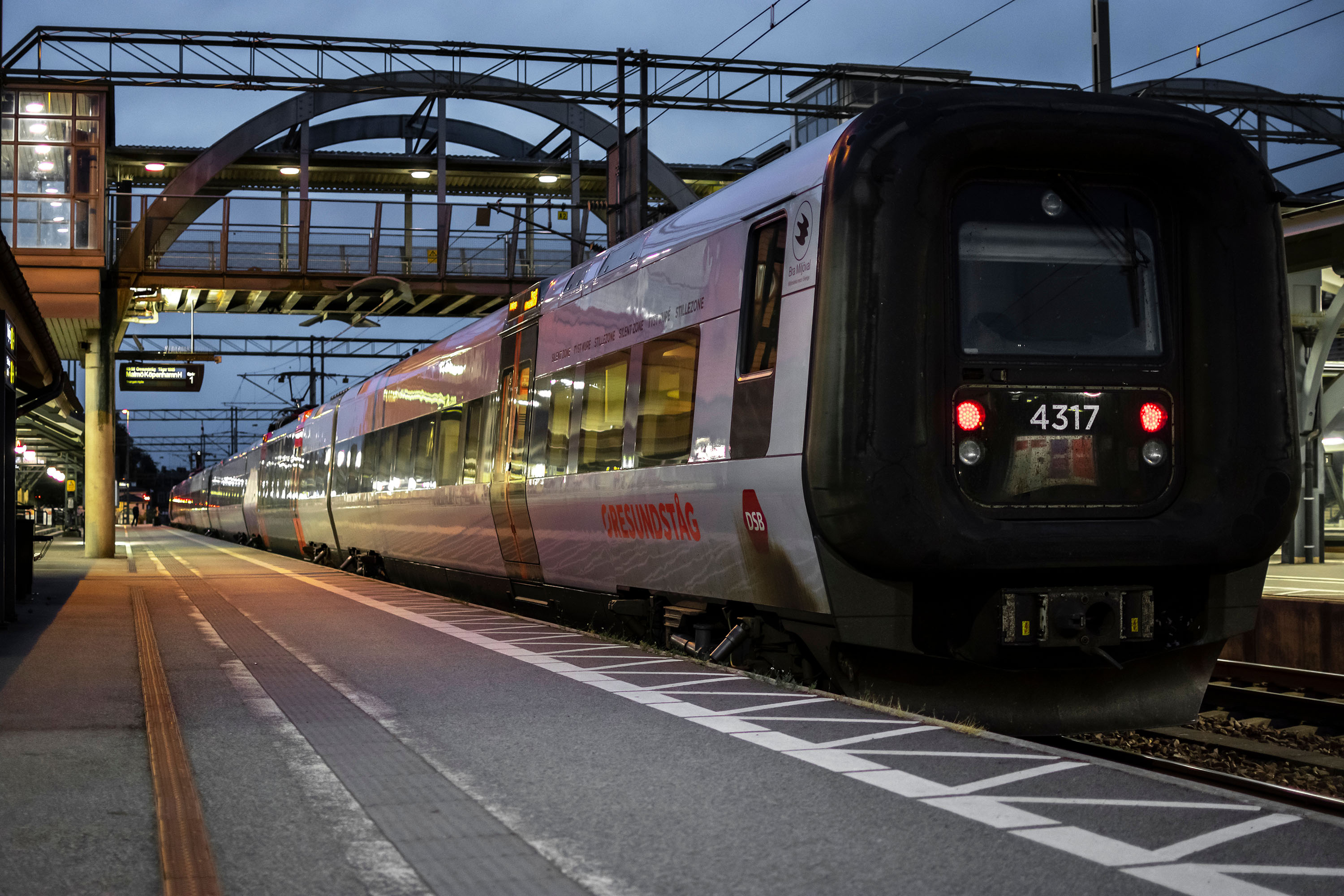 Öresundståg som står inne vid en perrong, i kvällsmörkret.