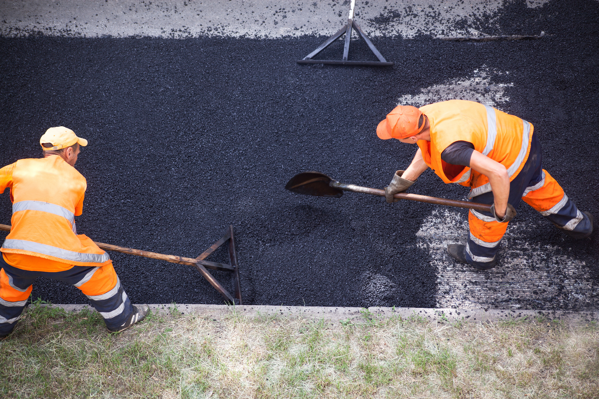 två män lägger asfalt på väg