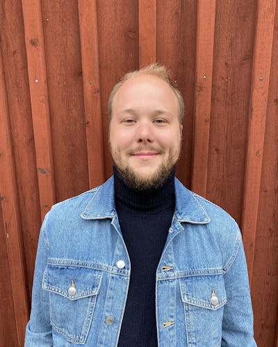 Porträttbild på Jakob Molinder, mot en röd trävägg.