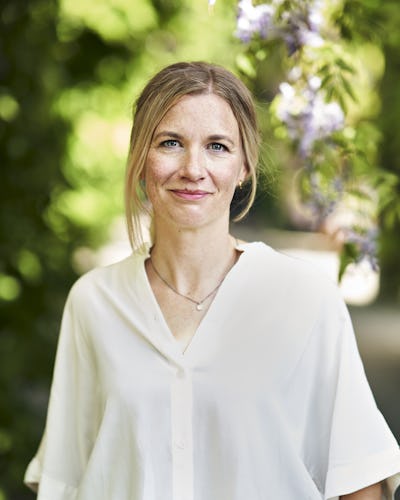 Poträttbild på Kerstin Enflo, mot en grönskande bakgrund.