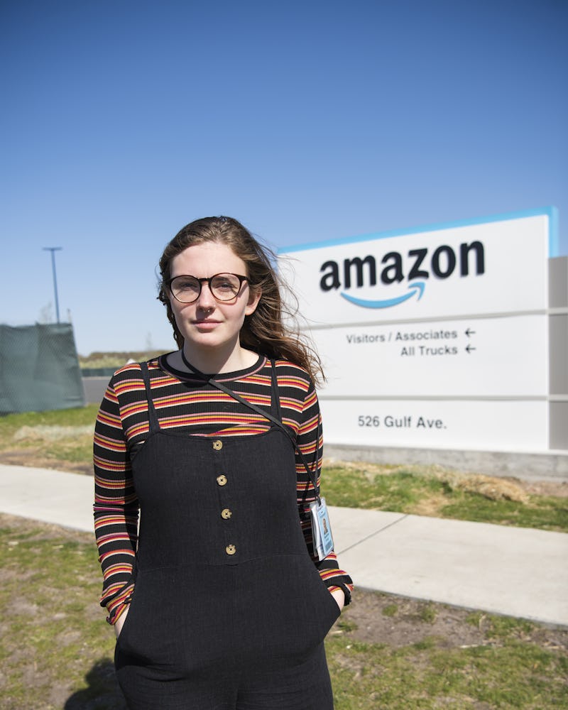 Madeline Wesley, i svarta hängselbyxor och randig tröja, står framför en skylt med Amazons logotyp.