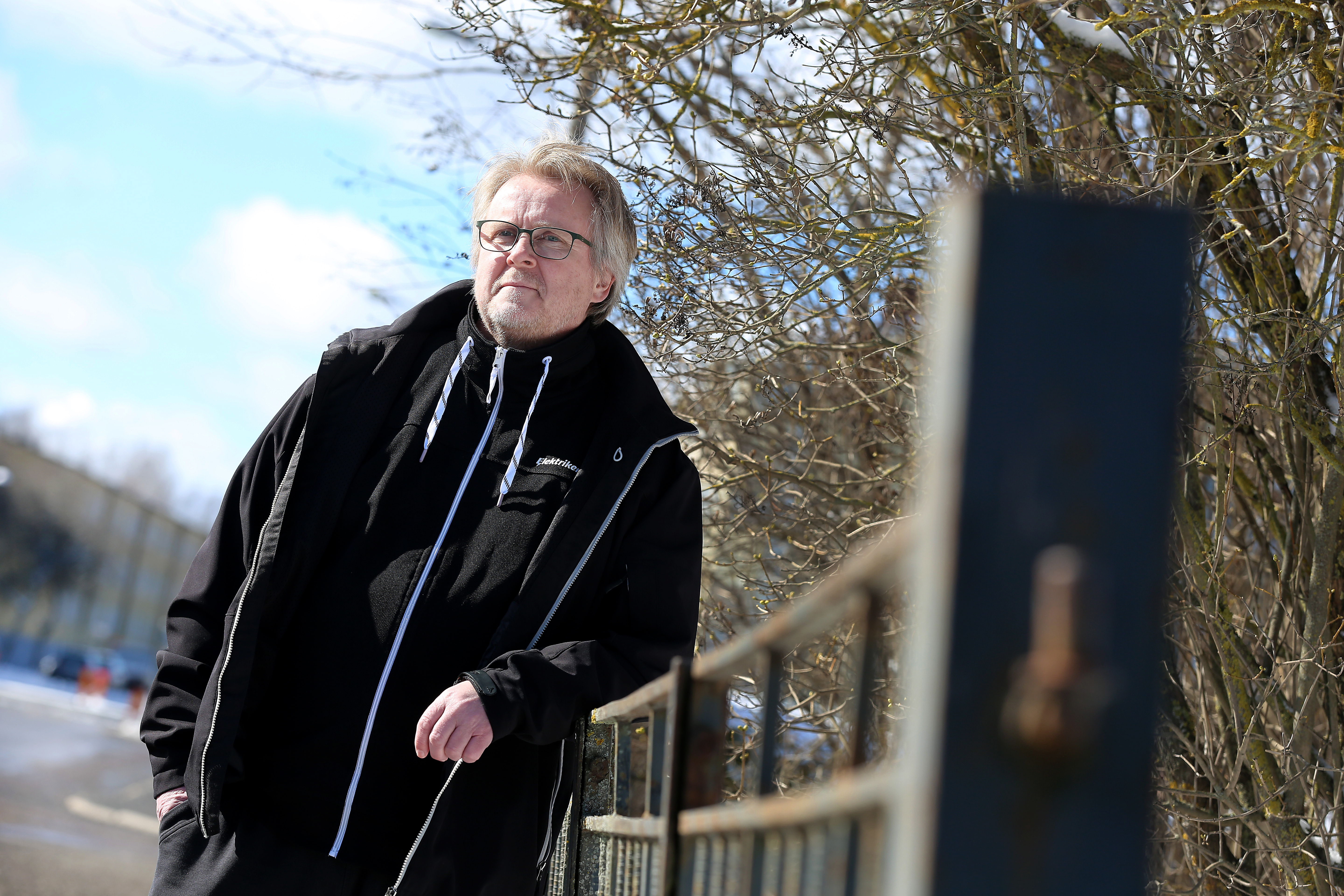 Mikael Karlsson, utomhus, lutar sig mot ett räcke.