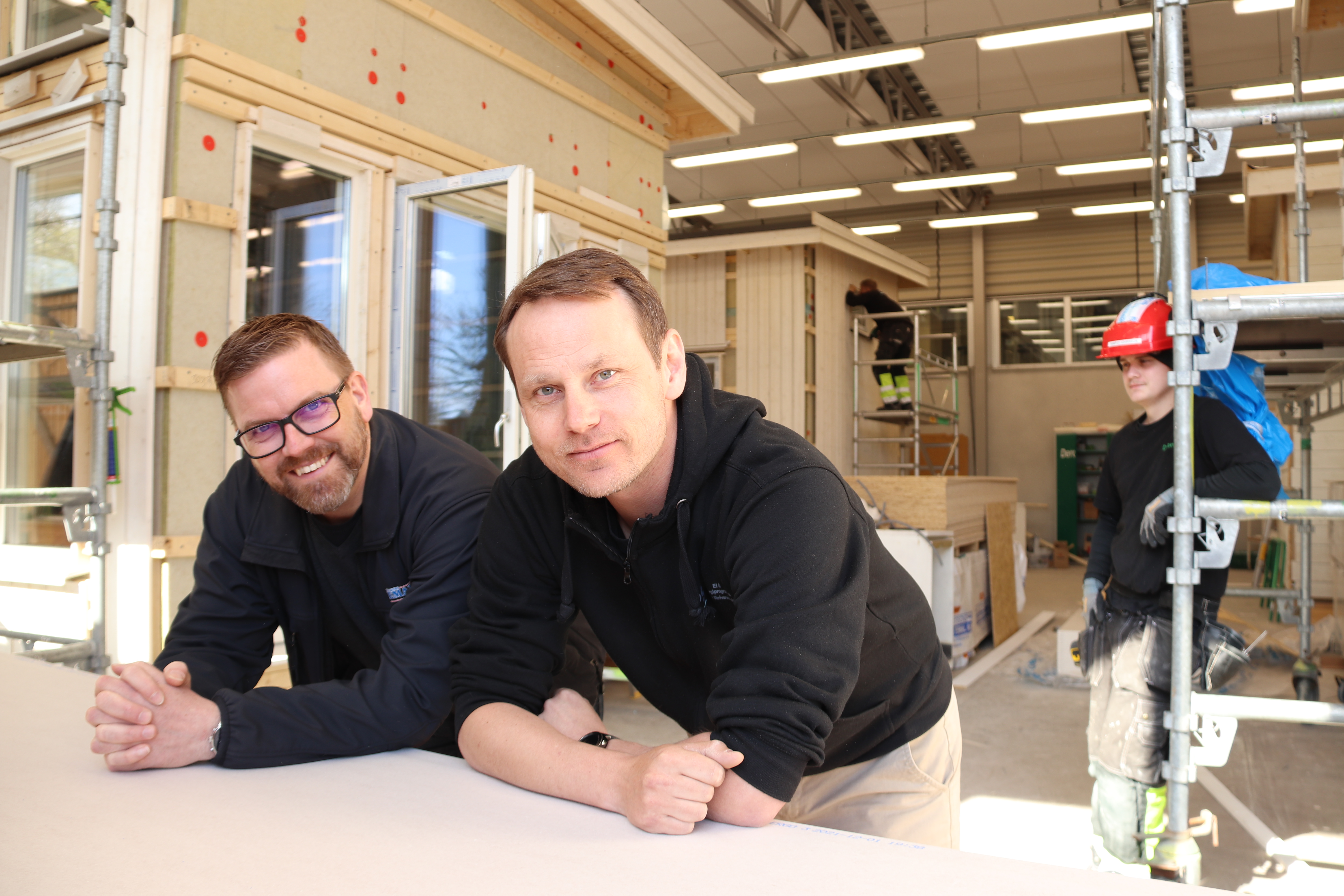 Björn Johnsson och Robert Staaf lutar sig mot ett bord inomhus.