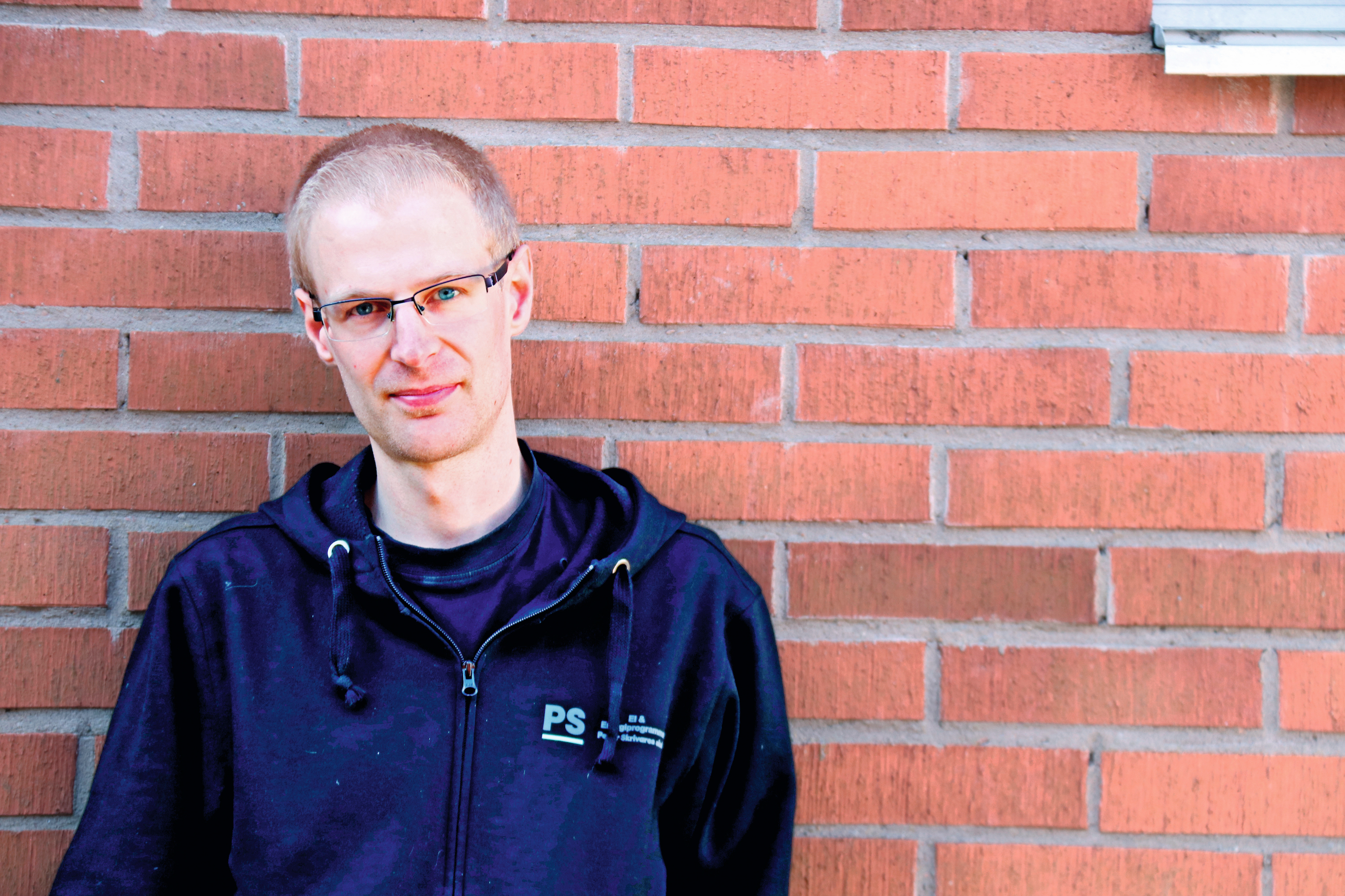 Daniel Eriksson framför en tegelvägg.