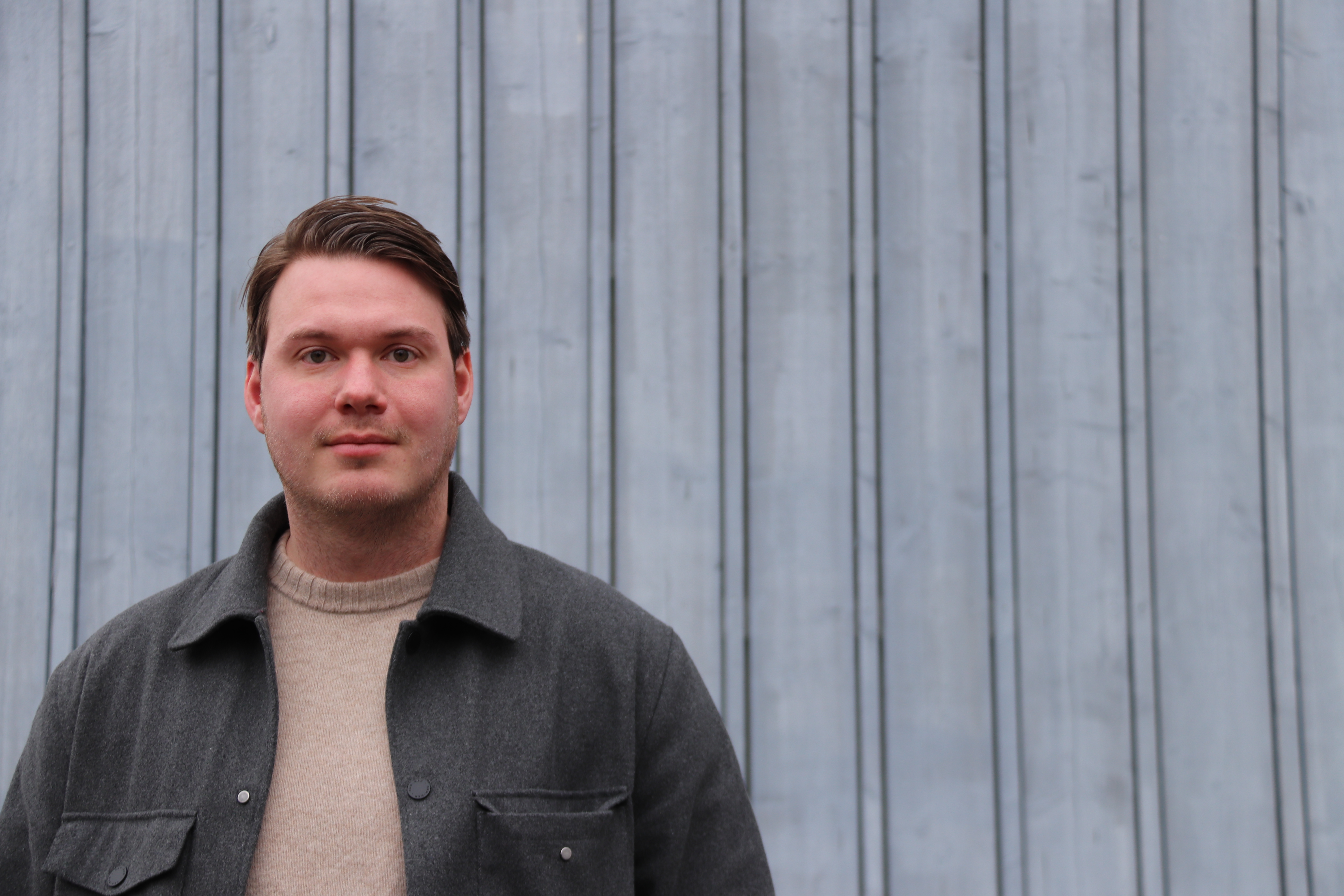 Sebastian Fjäll framför en grå vägg.