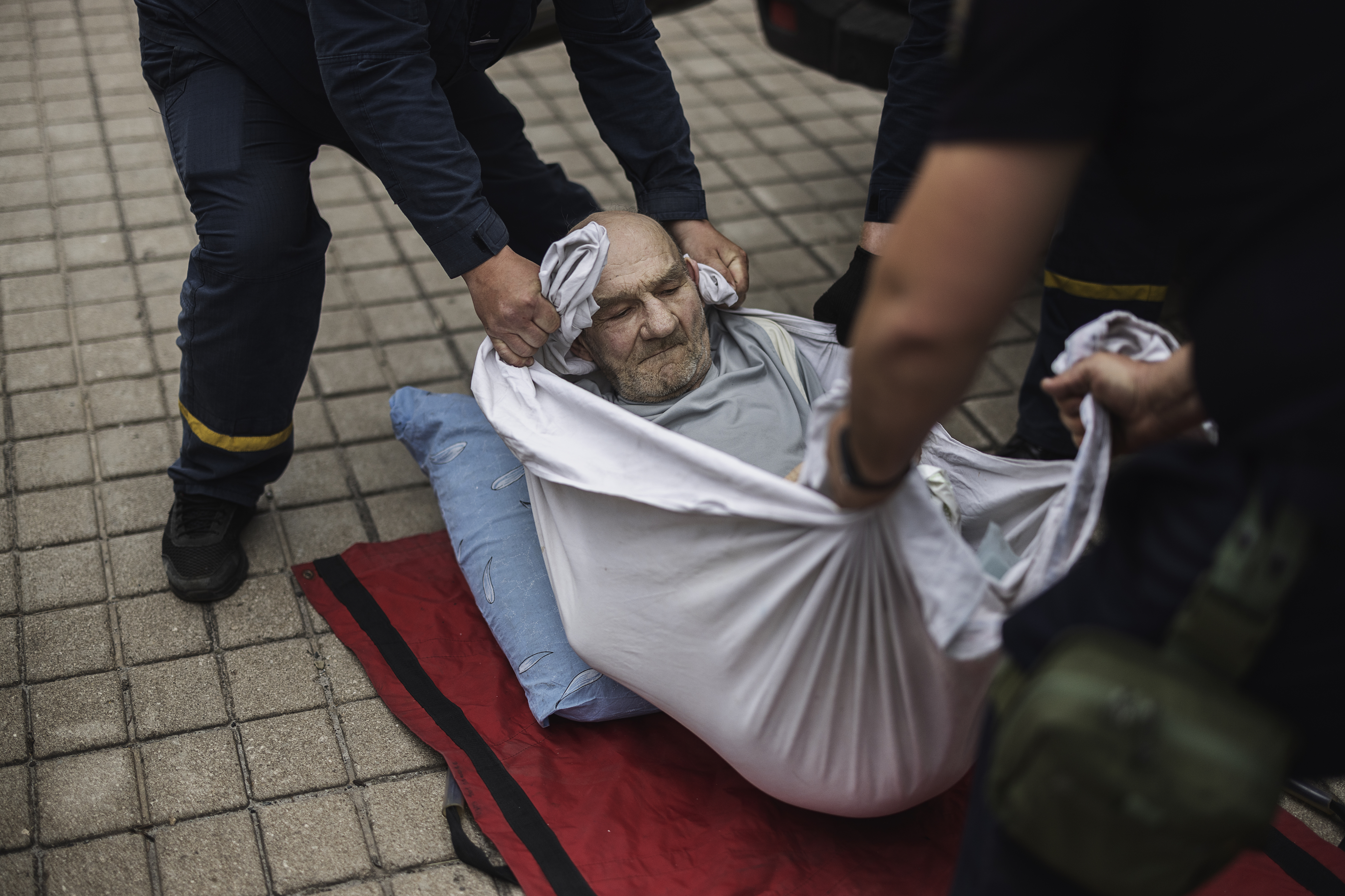 En man utan ben lyfts i en filt av ukrainsk tågpersonal.