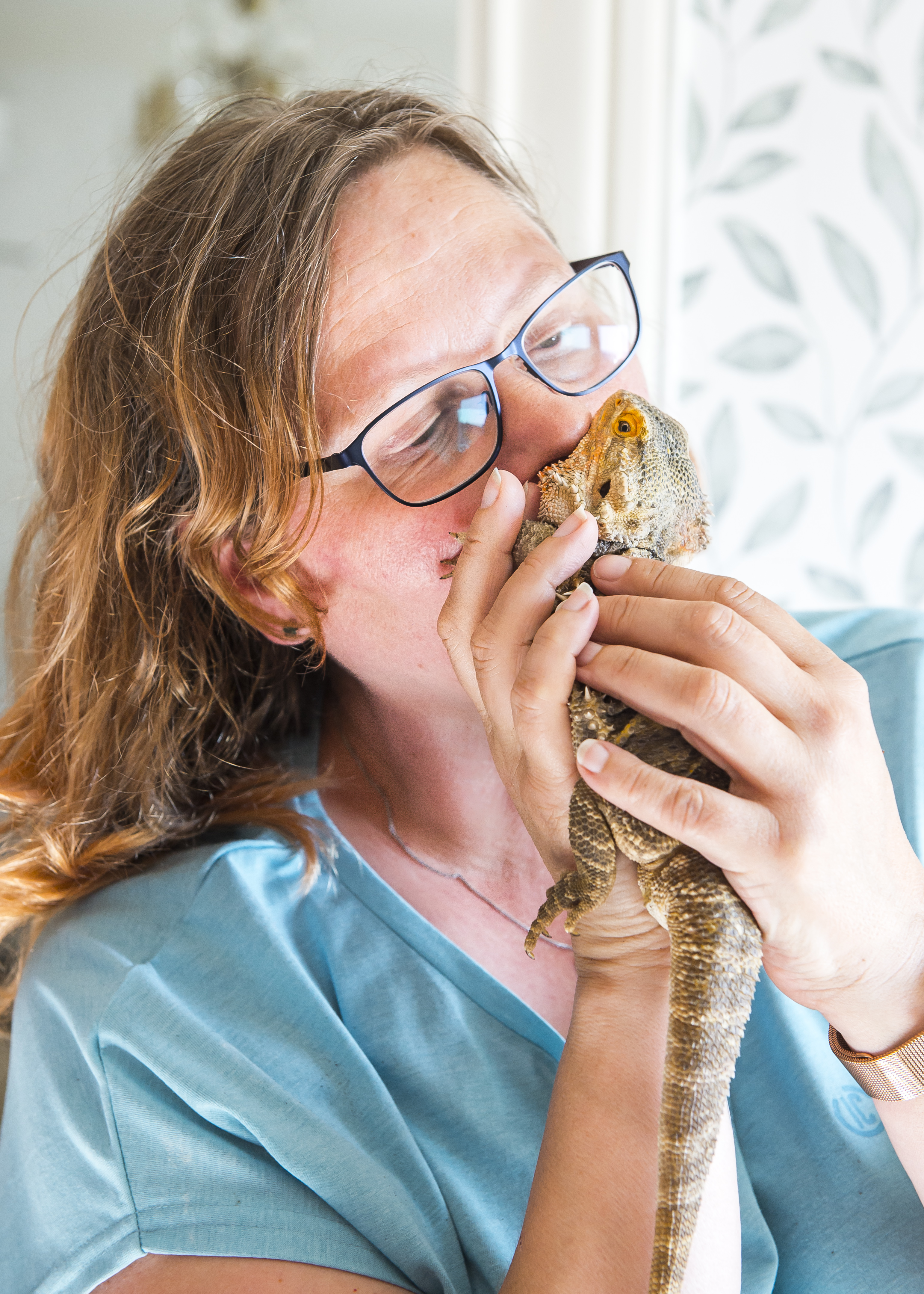 Tågvärden Britt-Inger Rydland gosar med en ödla i skiftande färger som hon håller i sina händer..