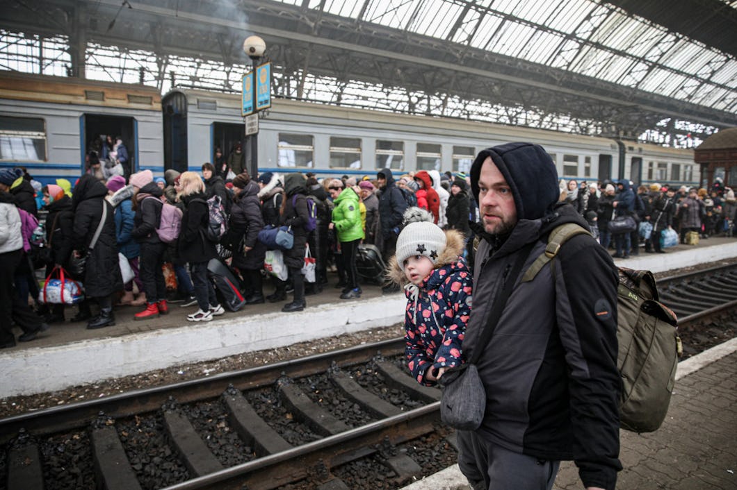 En ukrainsk man med en dotter i bärsele står på en tågperrong.