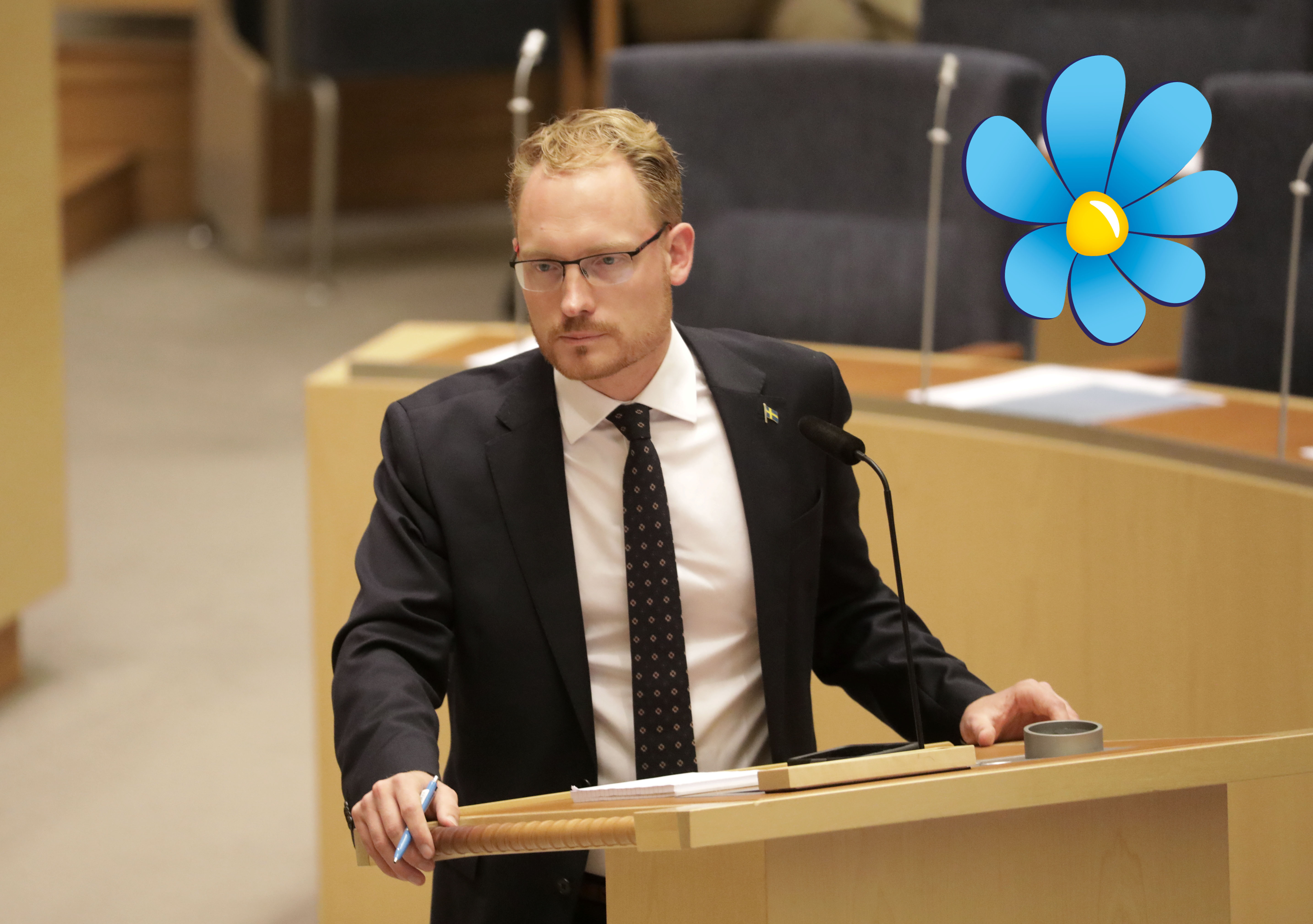 Aron Emilsson debatterar i riksdagen. Sverigedemokraternas logga inklistrad i bild.