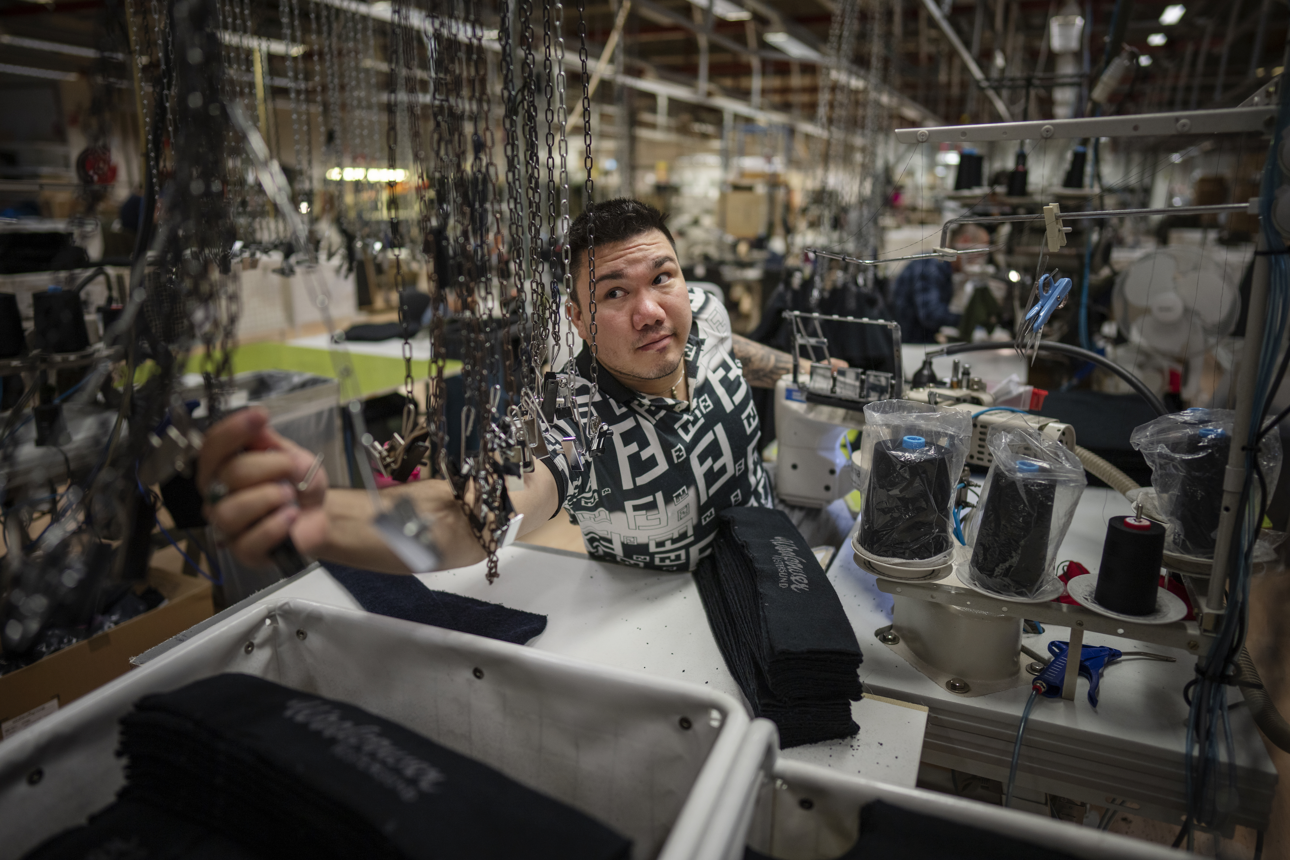 En man sträcker sig över ett sybord på Woolpowers fabrik i Östersund.