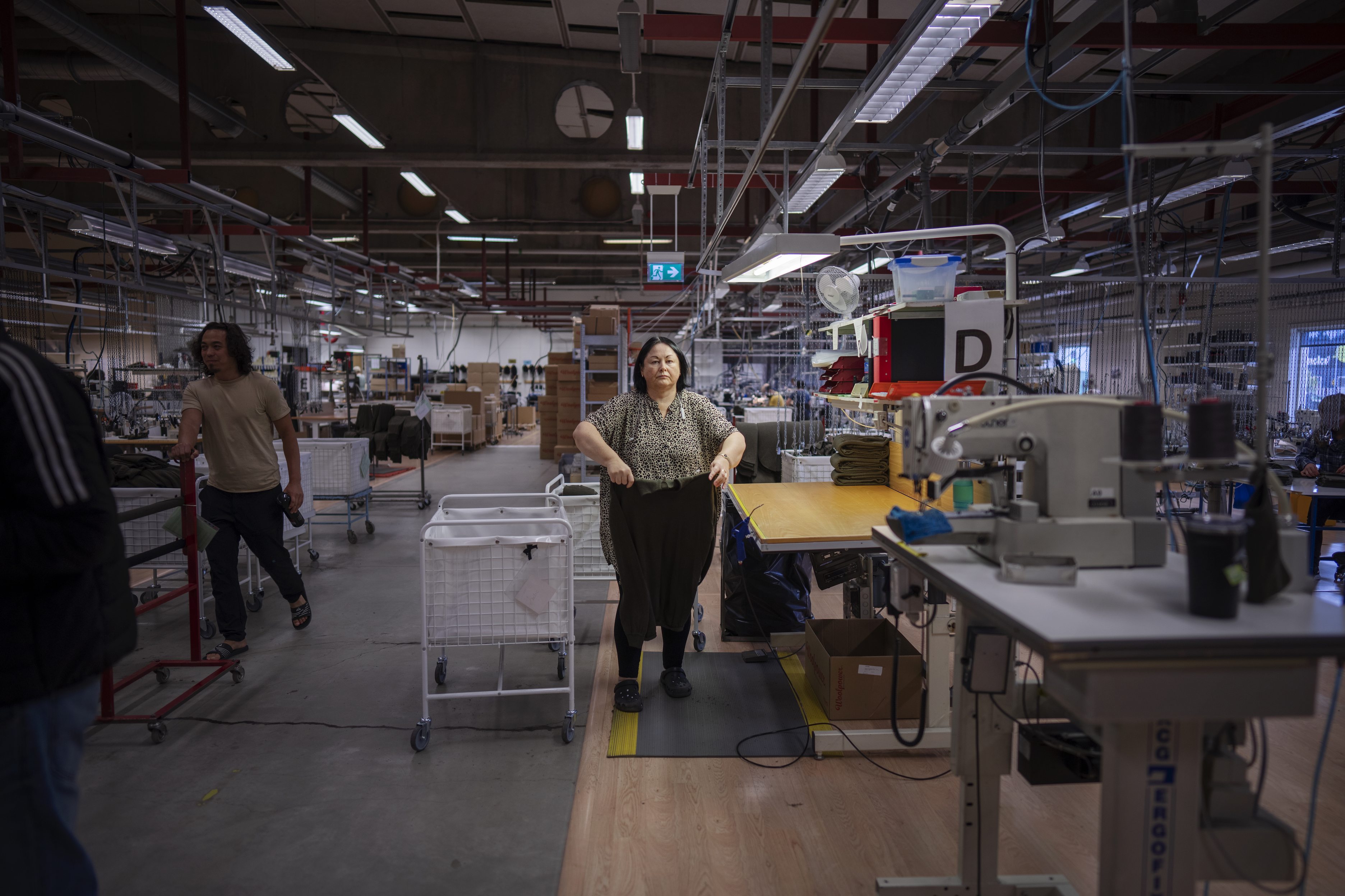 En kvinna viker kläder på ett fabriksgolv.