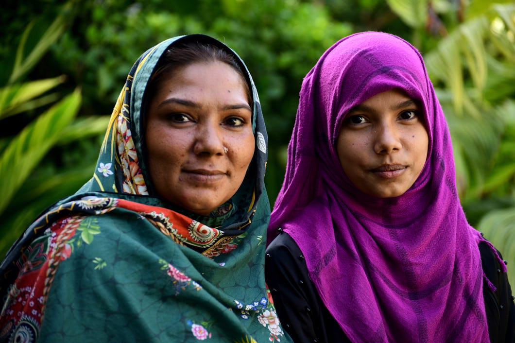 En pakistansk mamma i grön sjal (till vänster) och hennes dotter i lila sjal.